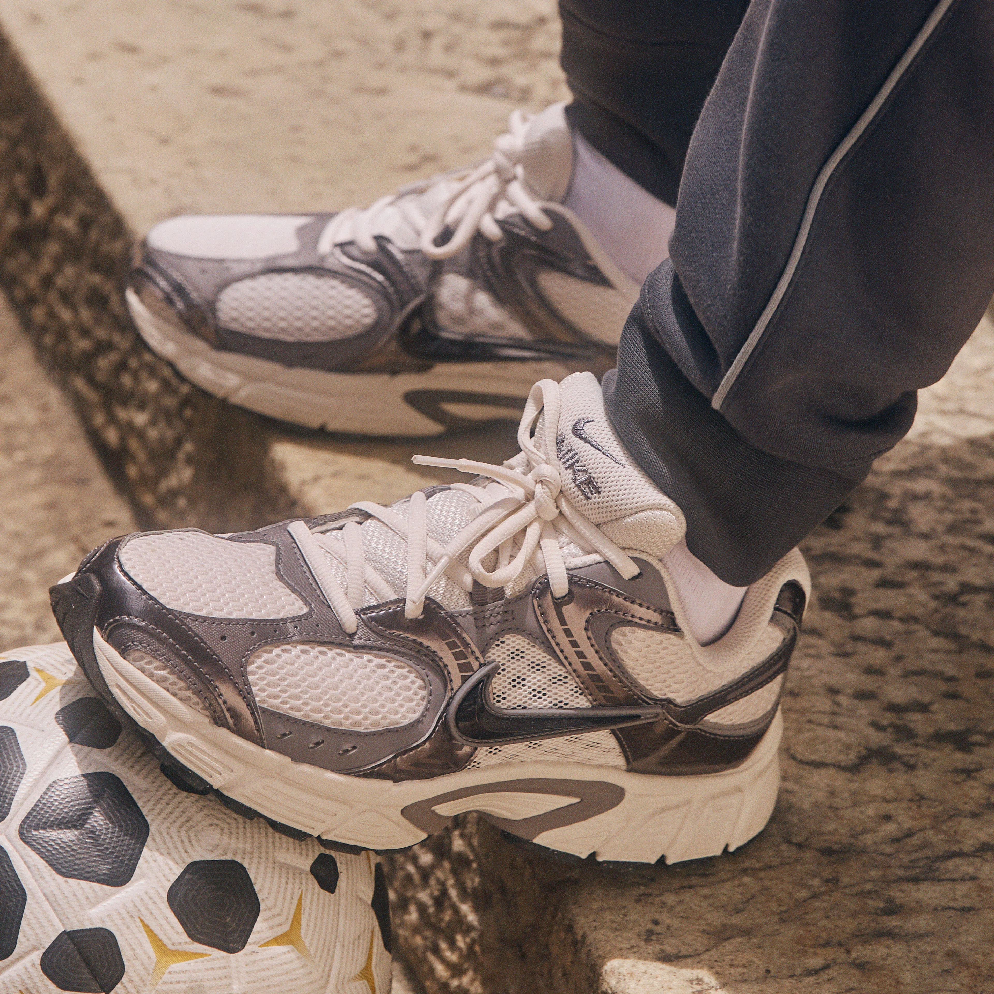 A person sits on stone steps with their foot resting on a soccer ball.