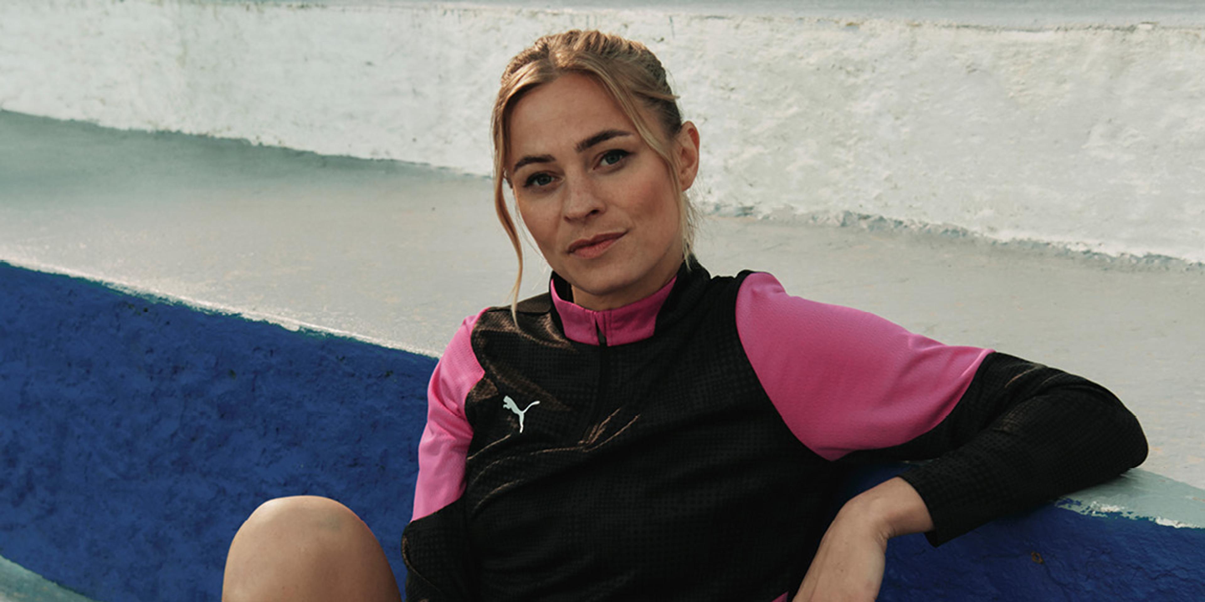 a woman in a pink and black jacket is sitting on the beach .
