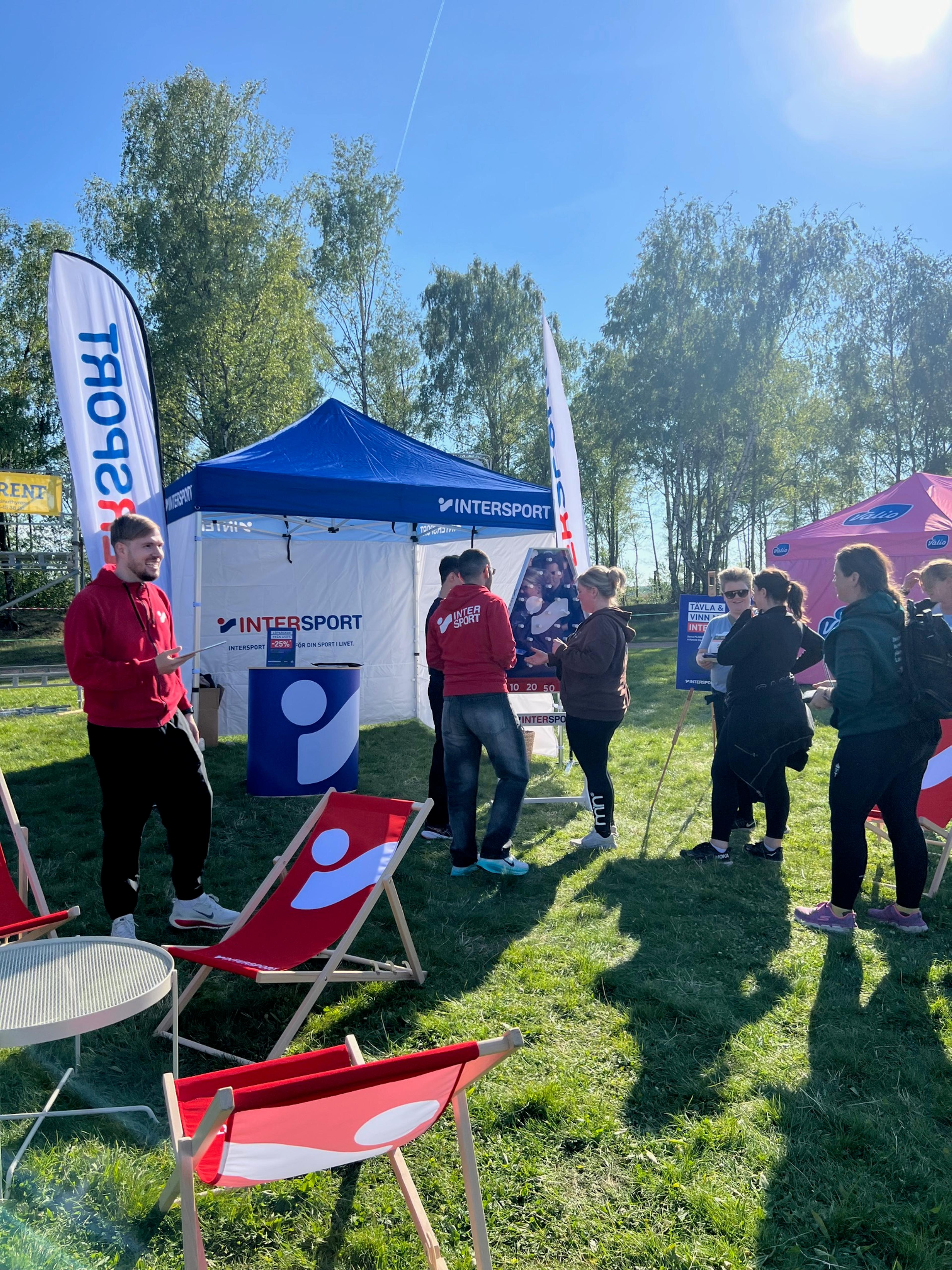 a group of people standing in front of a tent that says intersport