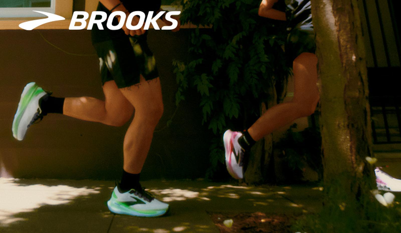 Two runners' legs in motion, wearing Brooks running shoes. Brooks logo in the top left.