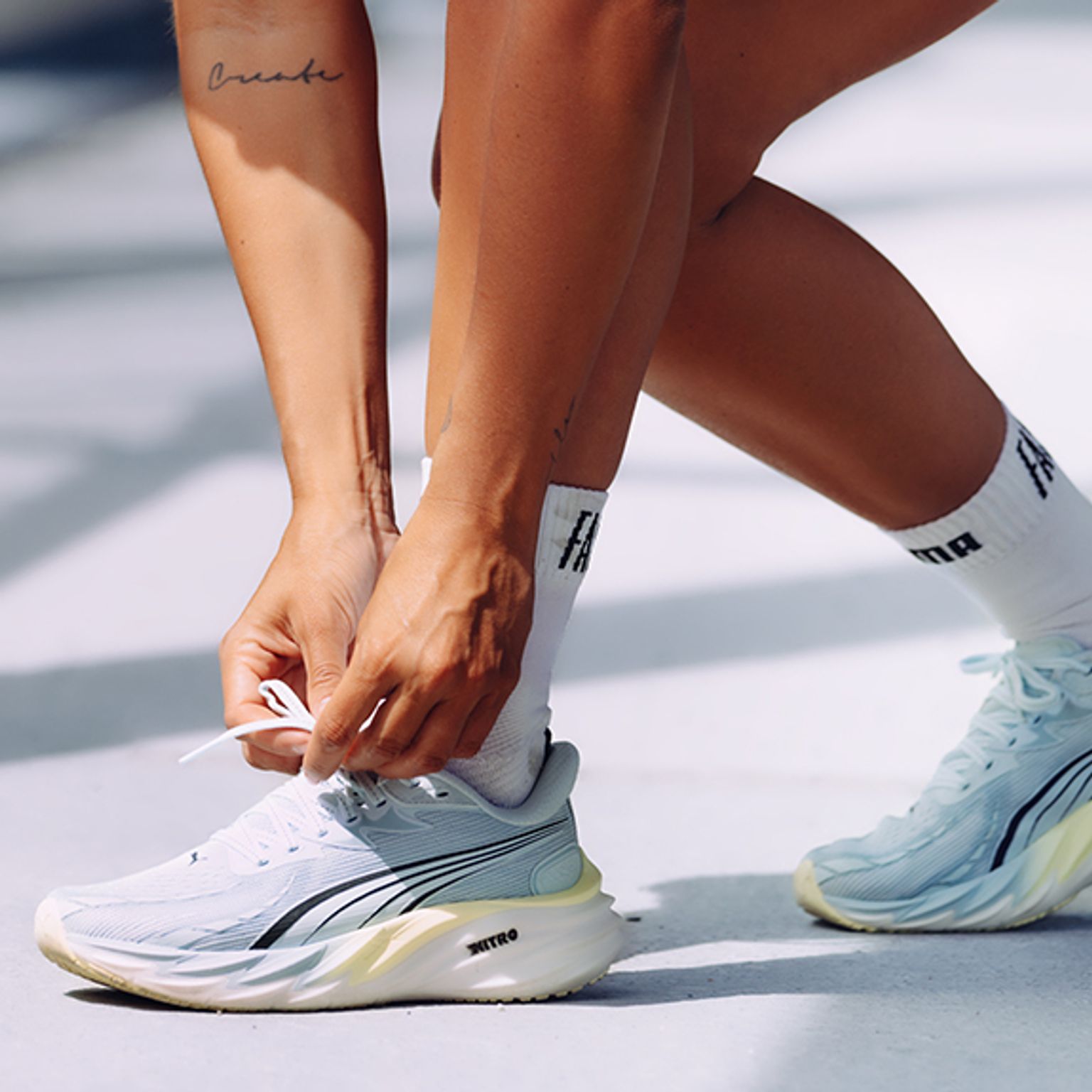 a person is tying their shoelaces on a white surface .