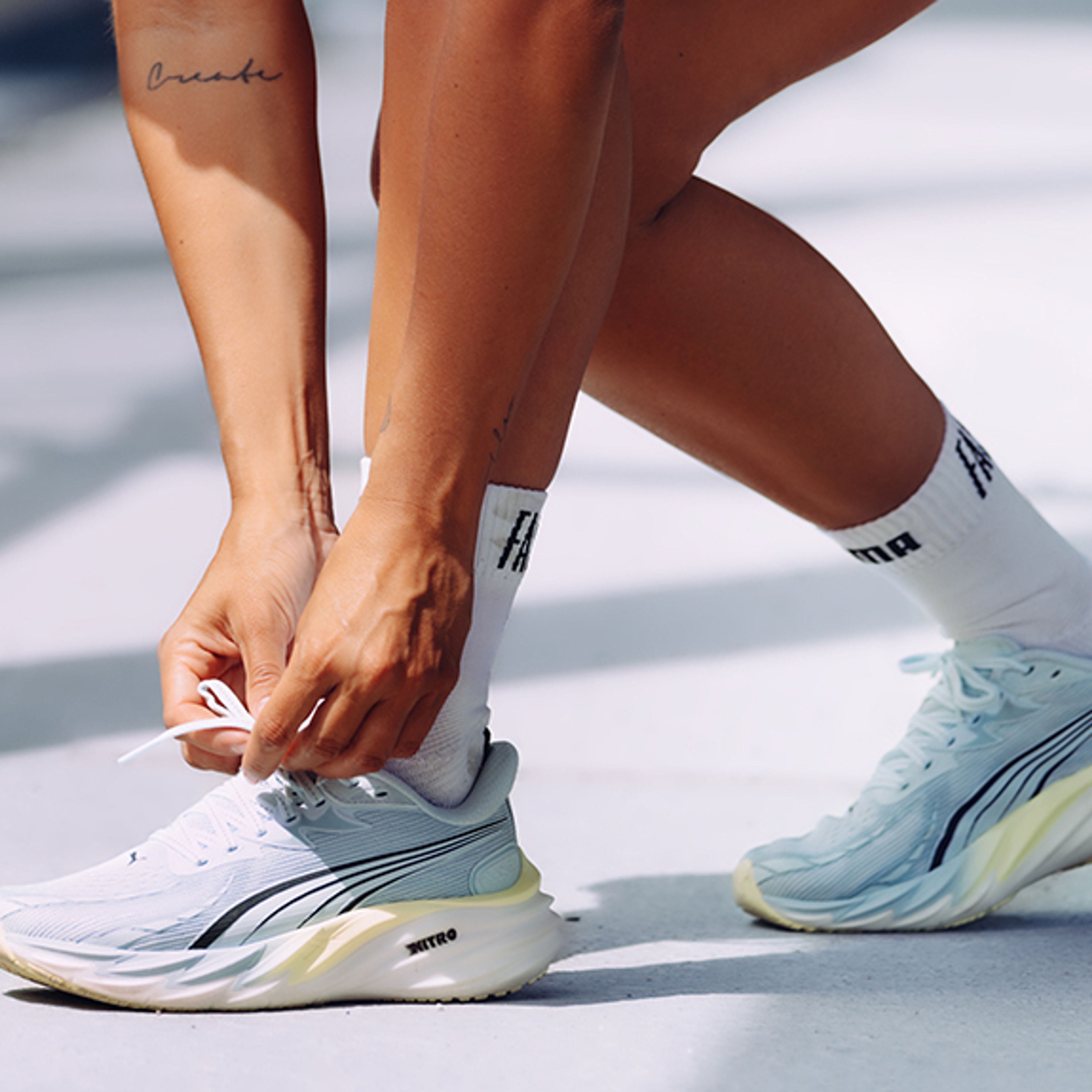 a person is tying their shoelaces on a white surface .