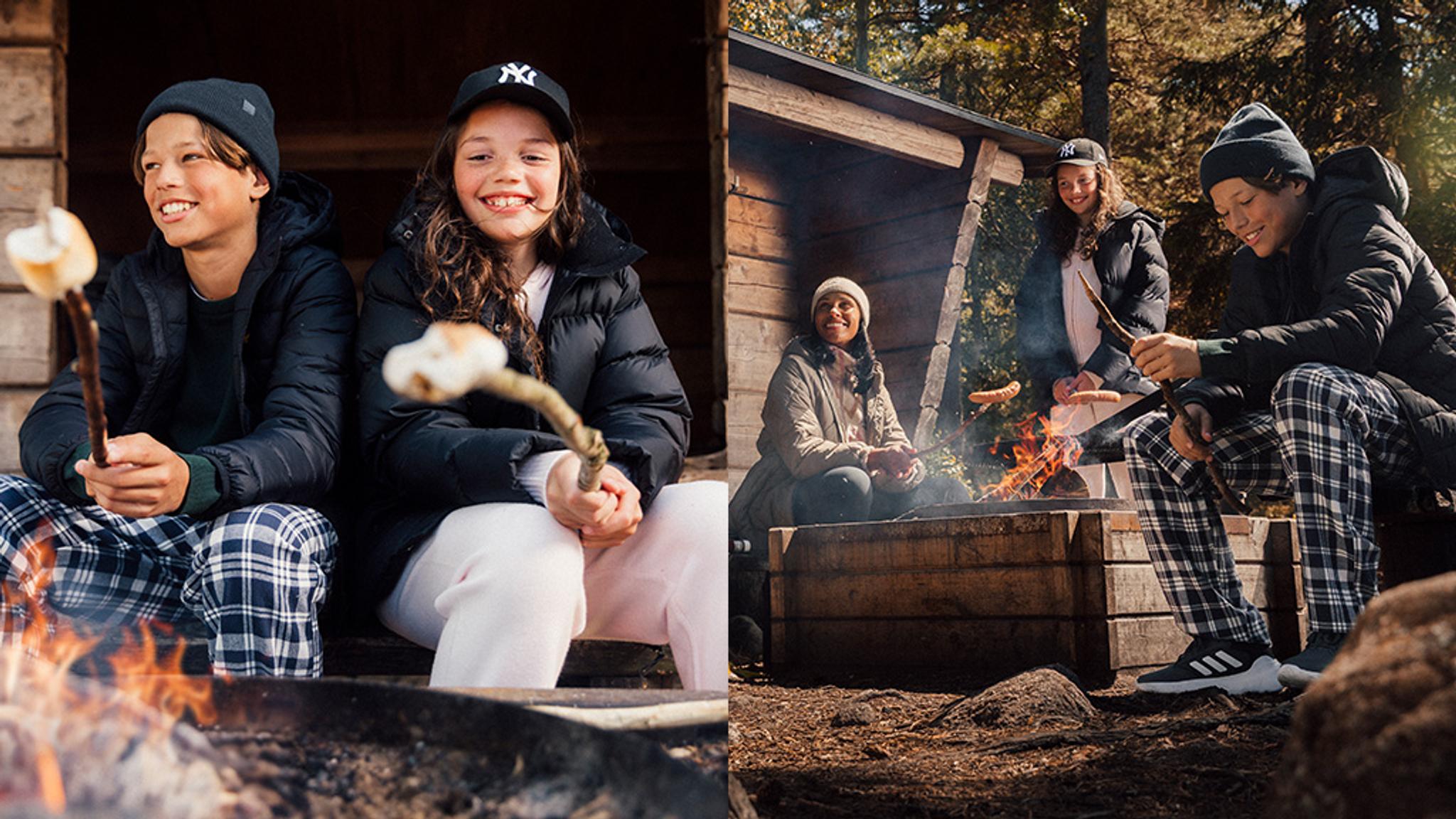 a group of children are sitting around a campfire roasting marshmallows .