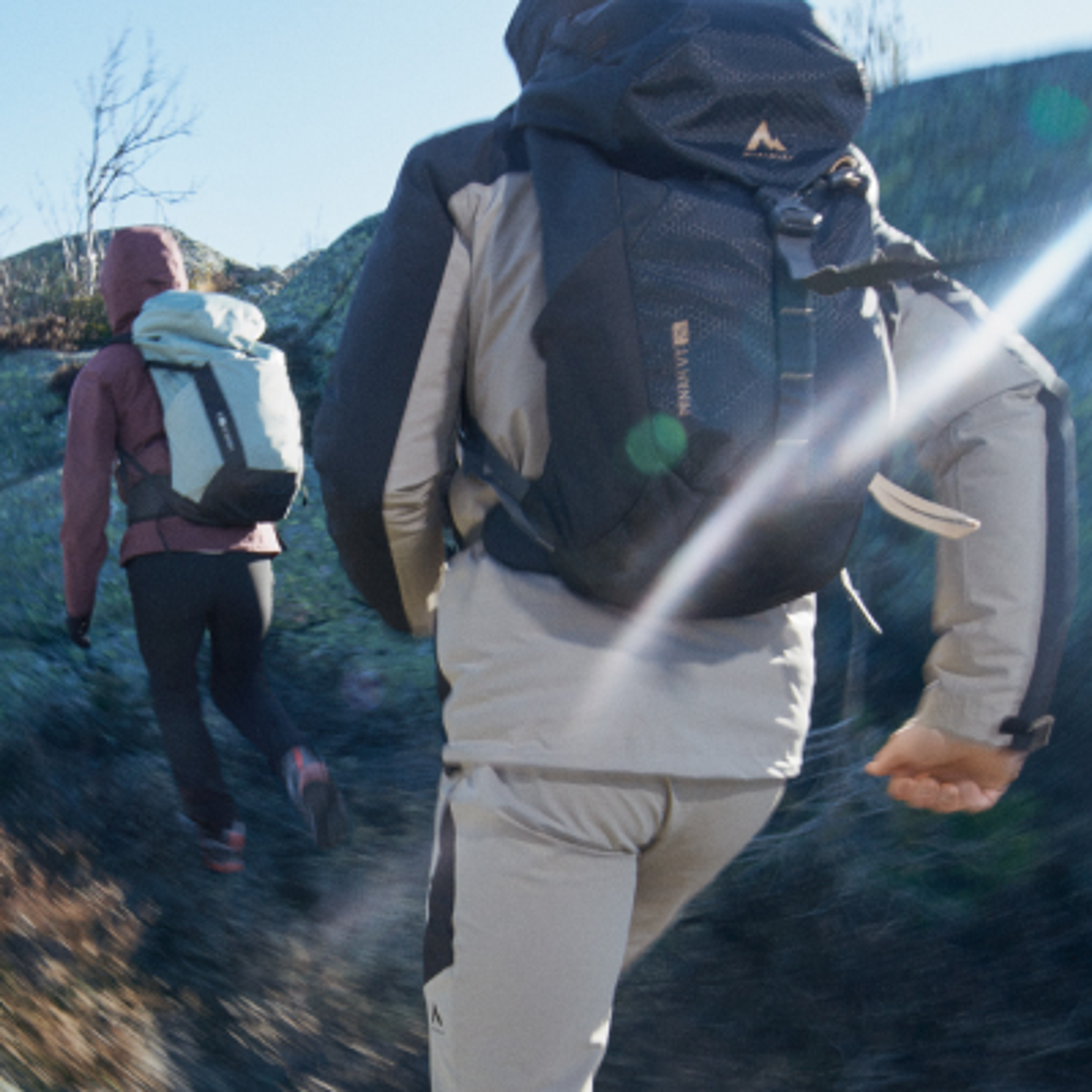 Man hiking with a backpack and mirrored sunglasses on a rocky trail.