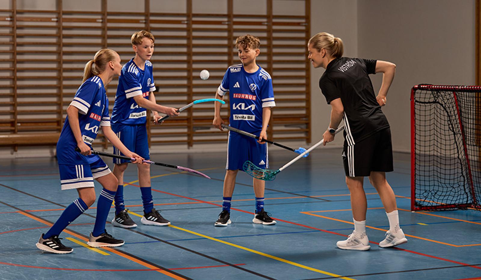 a group of young people are playing floorball in a gym .