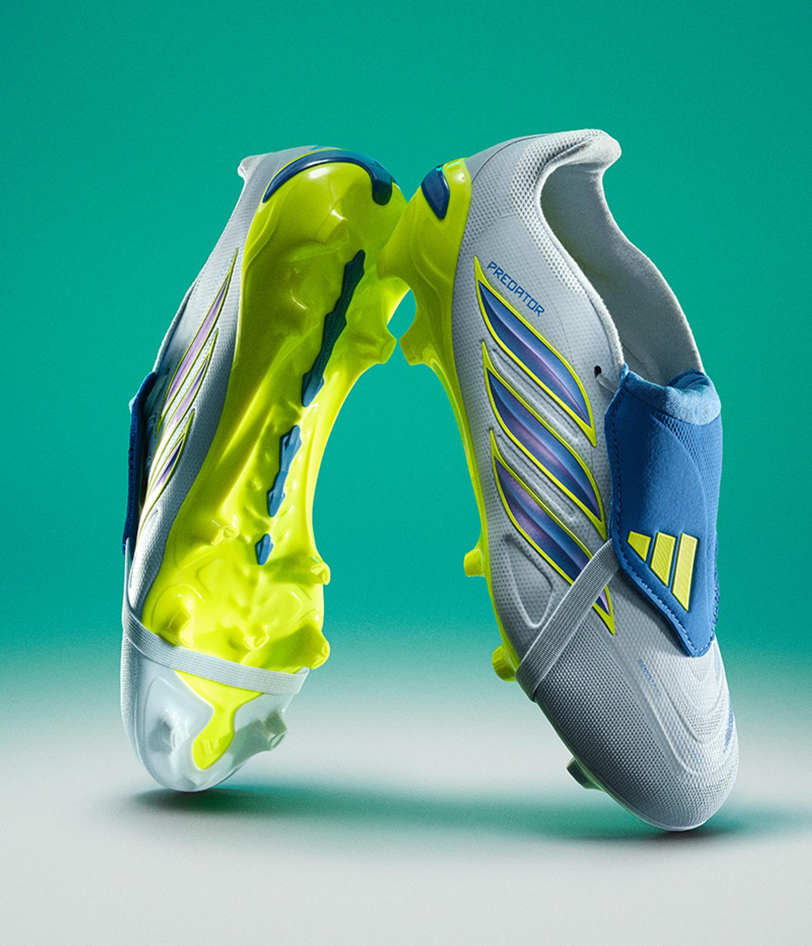 Two light grey, neon yellow, and blue Predator soccer cleats face each other against a teal background.