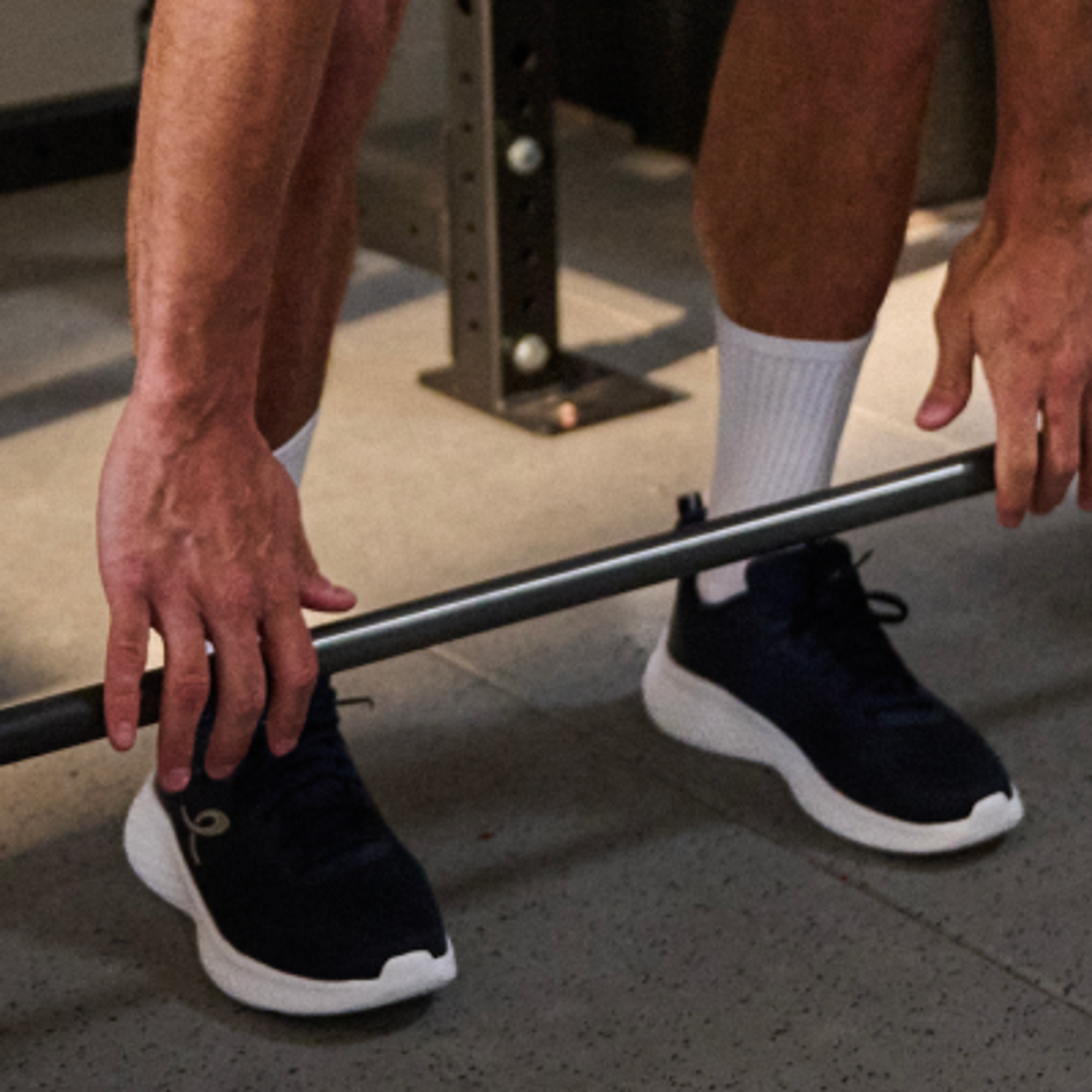 Close-up of a person's hands gripping a barbell in a gym.