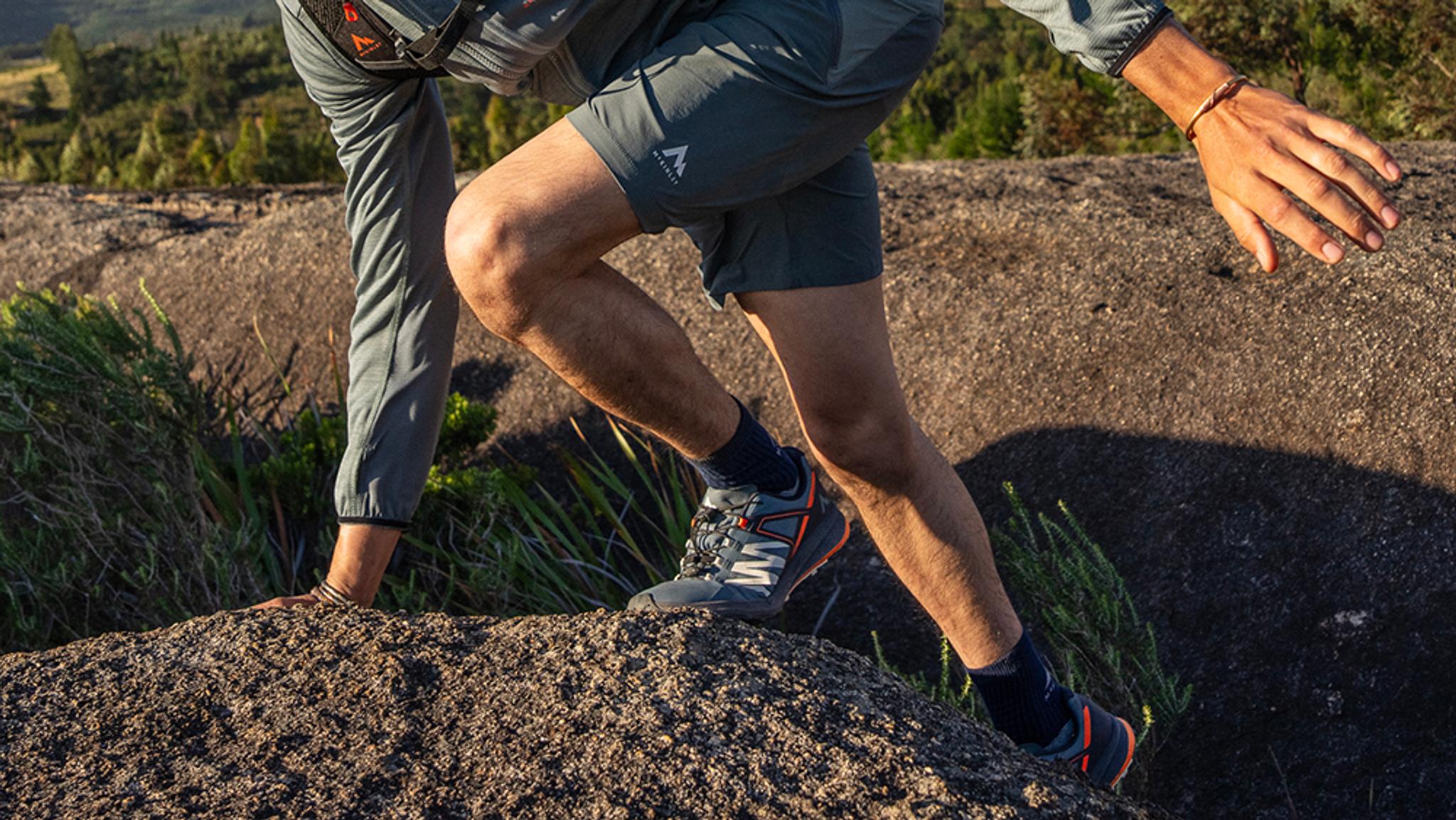 a person wearing a pair of salomon shoes is walking through a puddle of water .
