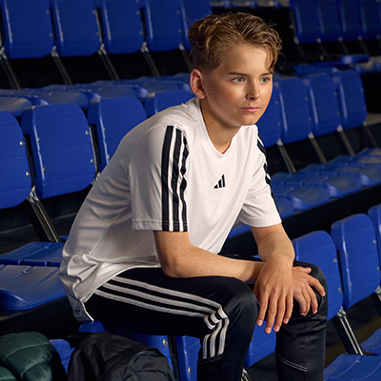 a young boy is sitting on a blue chair in a stadium .