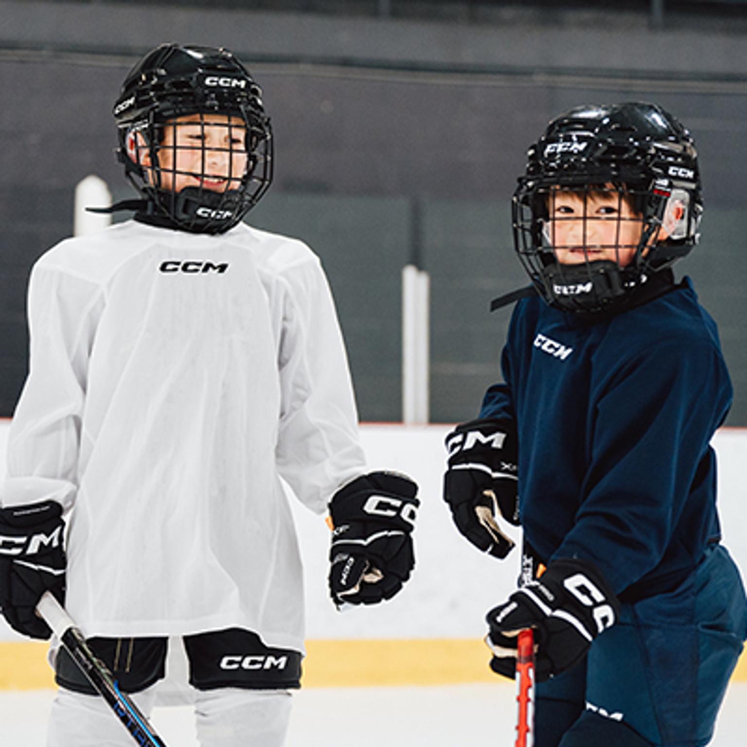 two young boys are playing ice hockey on a rink .