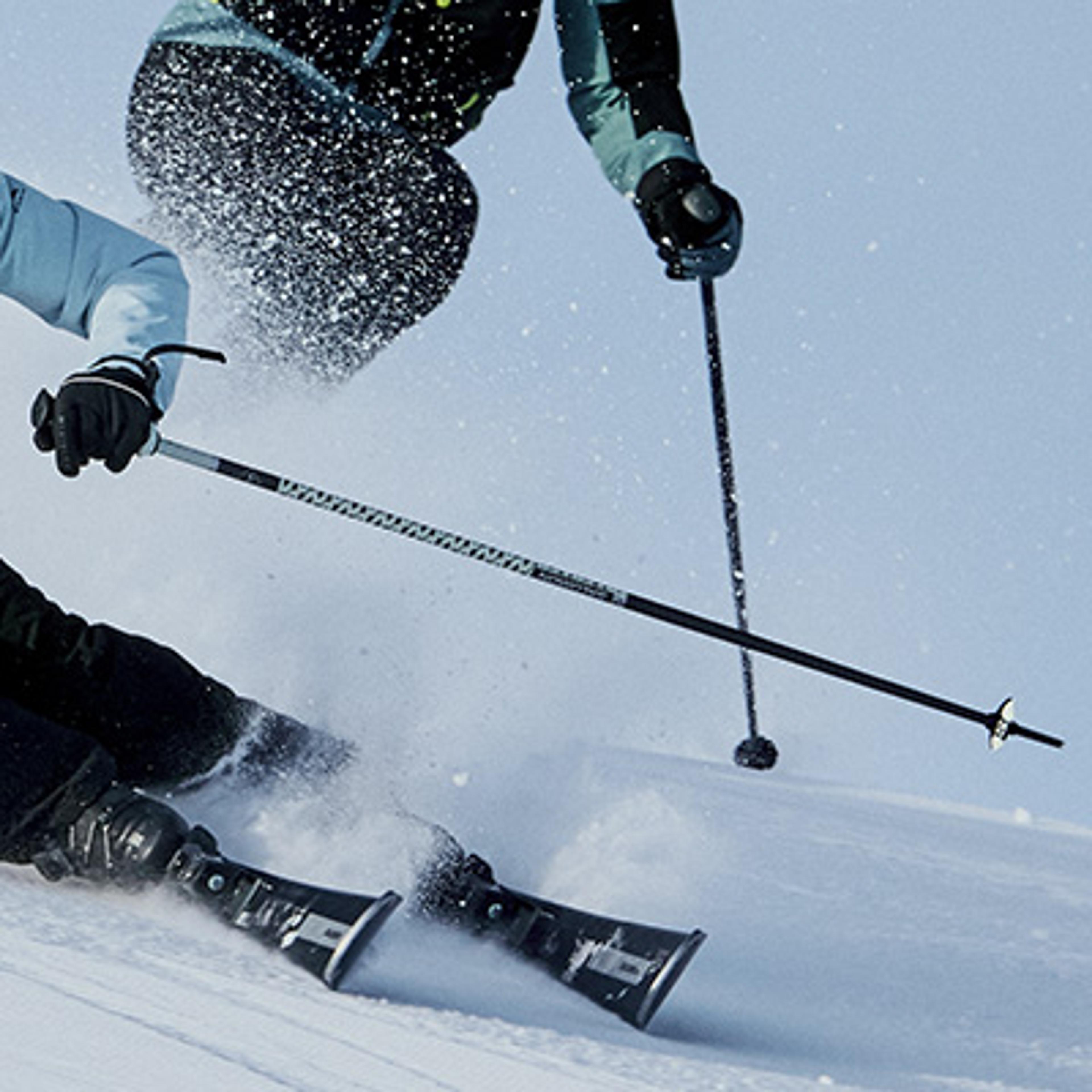 A skier carves a turn, kicking up a spray of snow.