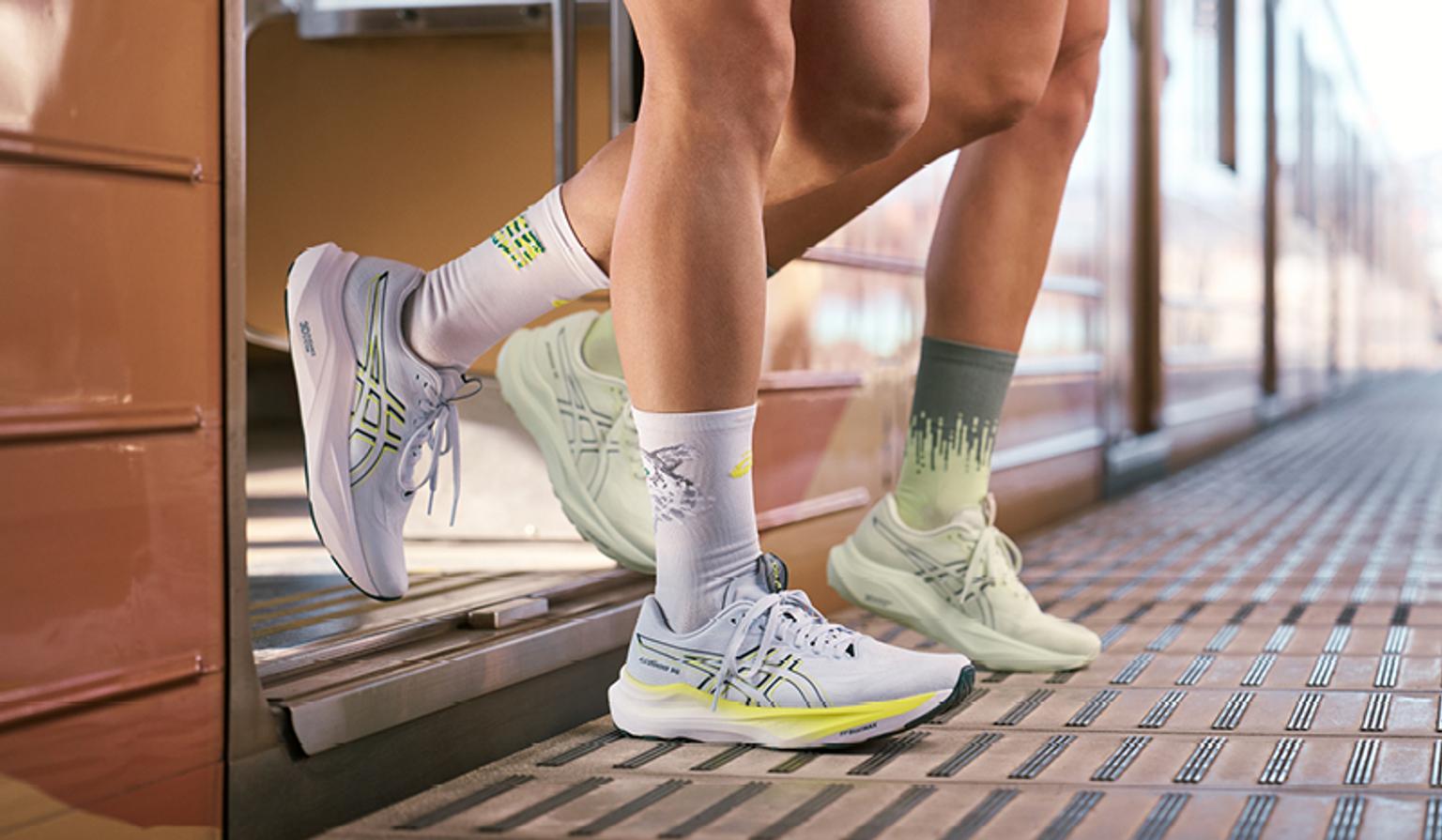 a couple of people wearing socks and running shoes are standing next to each other on a train .