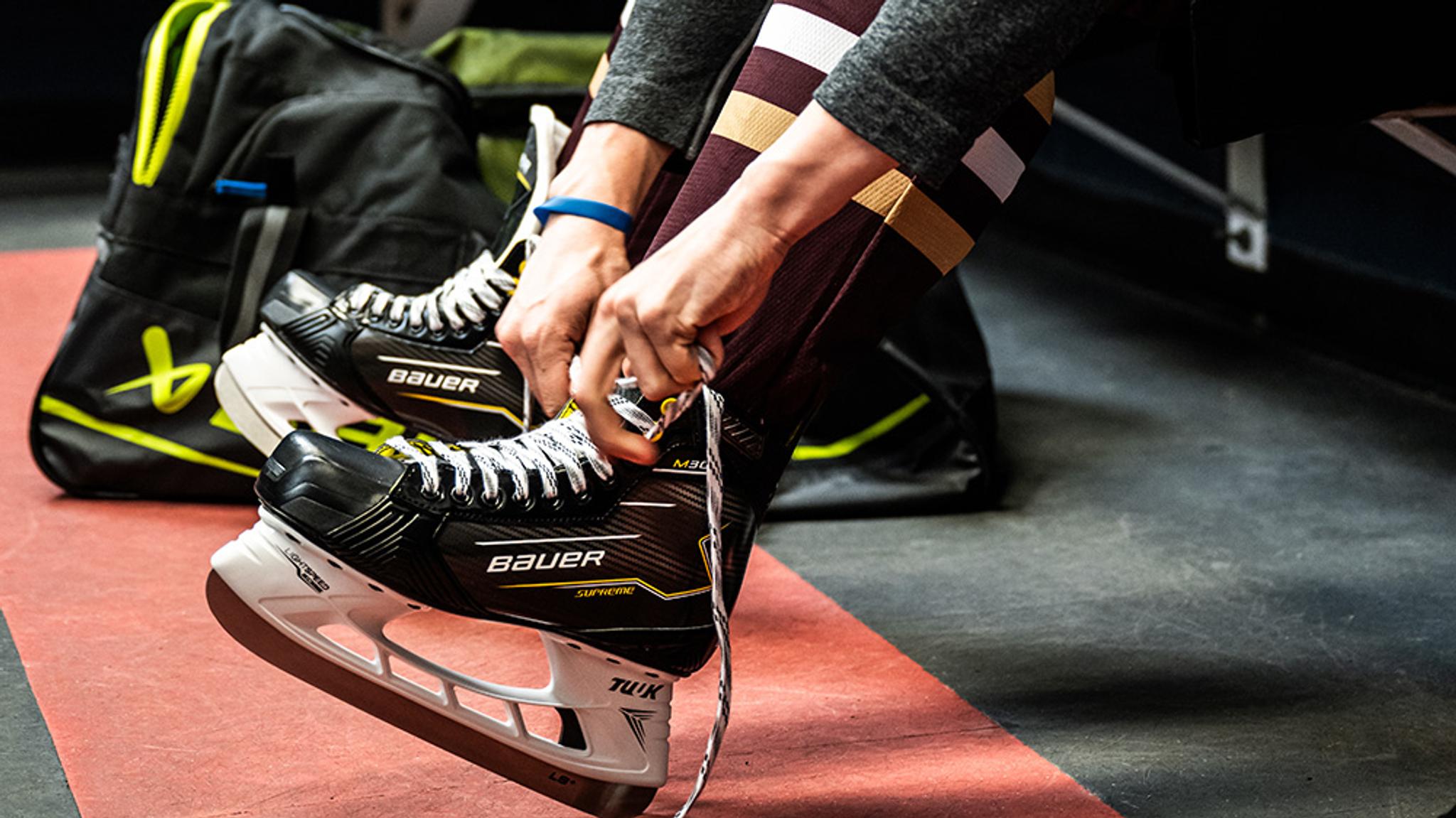 a person is tying their ice hockey skates .