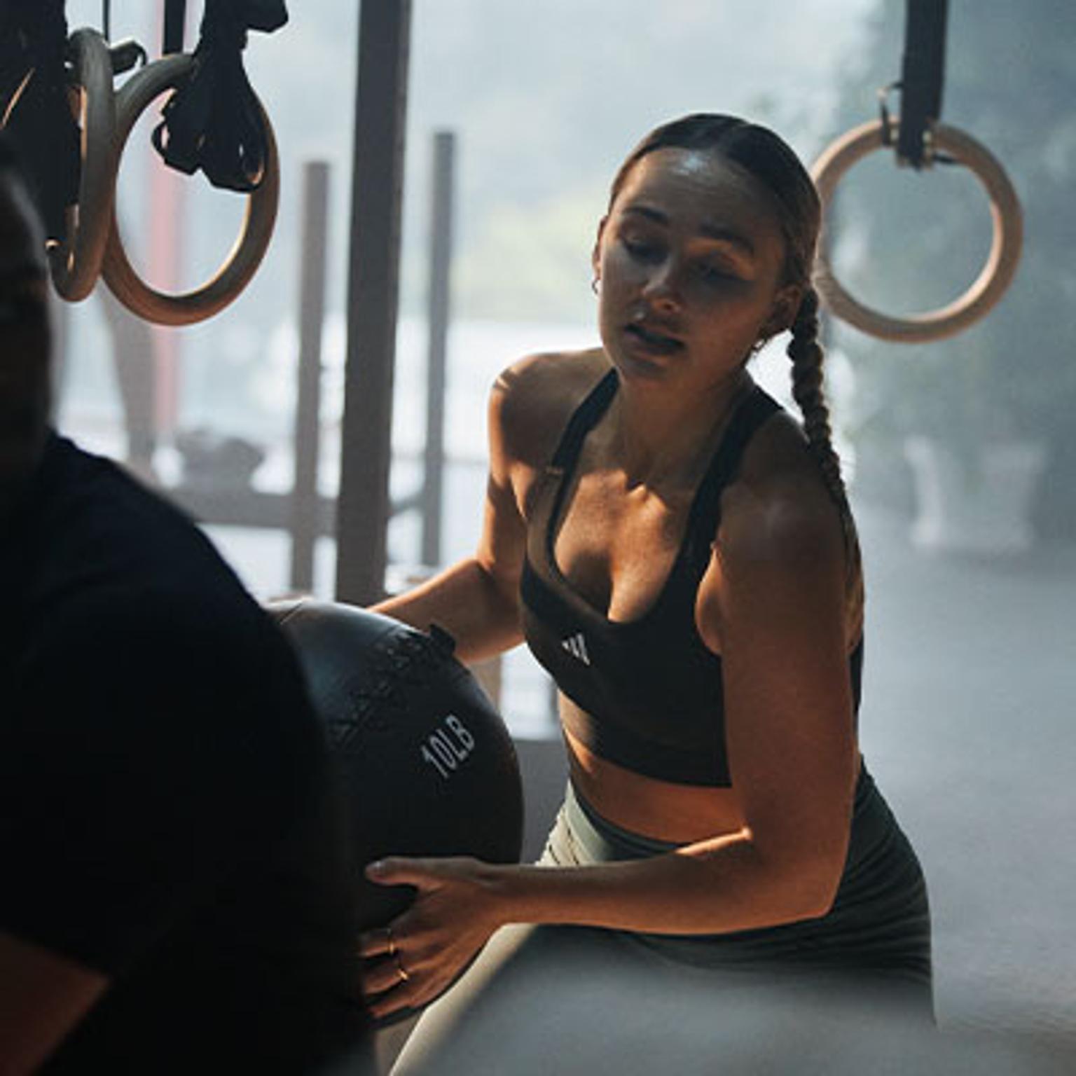 a woman is holding a medicine ball in a gym .