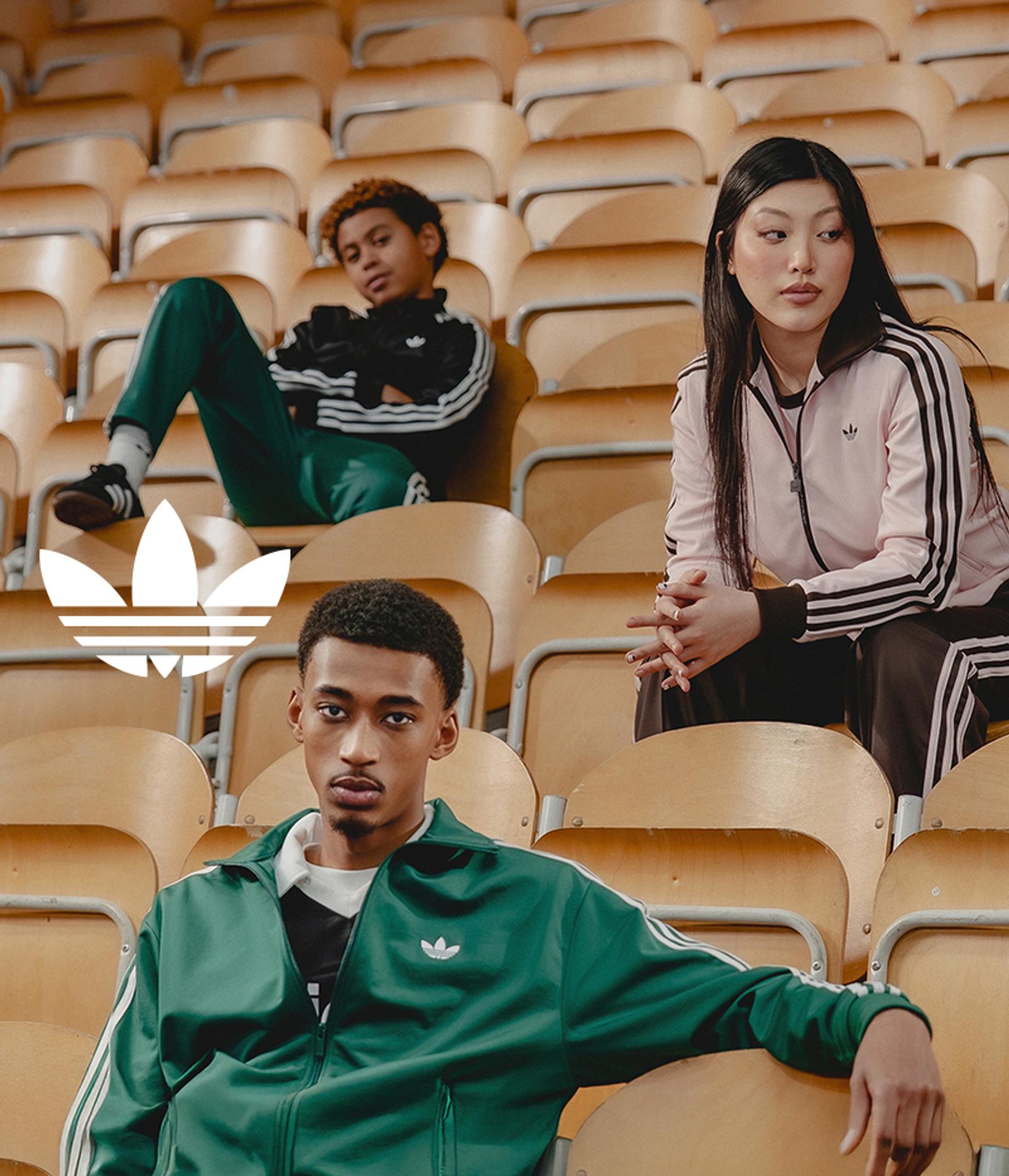 Three young people in Adidas tracksuits sitting in bleachers, with the Adidas Trefoil logo.