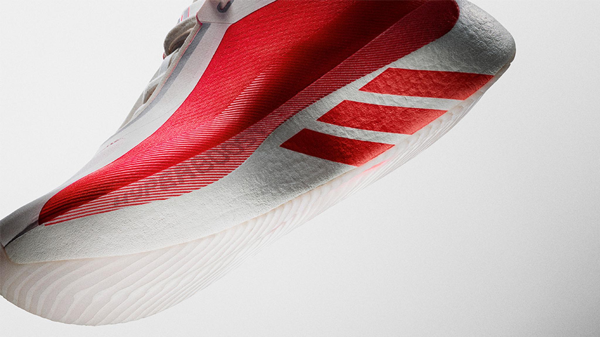 Close-up of a white Adidas sports shoe with a red diagonal stripe and the iconic three red stripes.