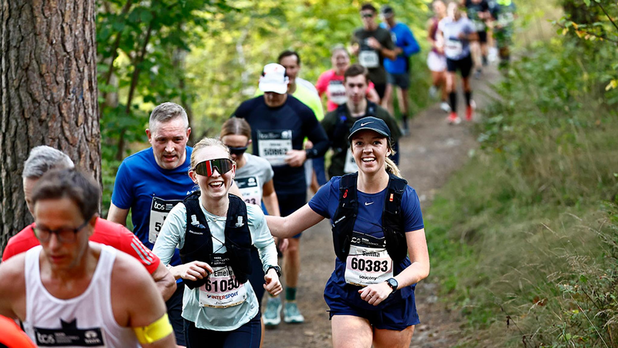 Smiling runners on a forest trail during a race, Lidingöloppet