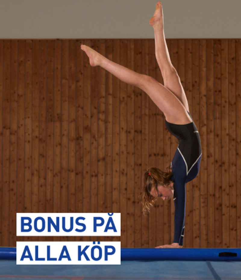 A gymnast in a black and blue leotard performs a handstand with one leg extended high on a blue mat. Text overlay: BONUS PÅ ALLA KÖP.
