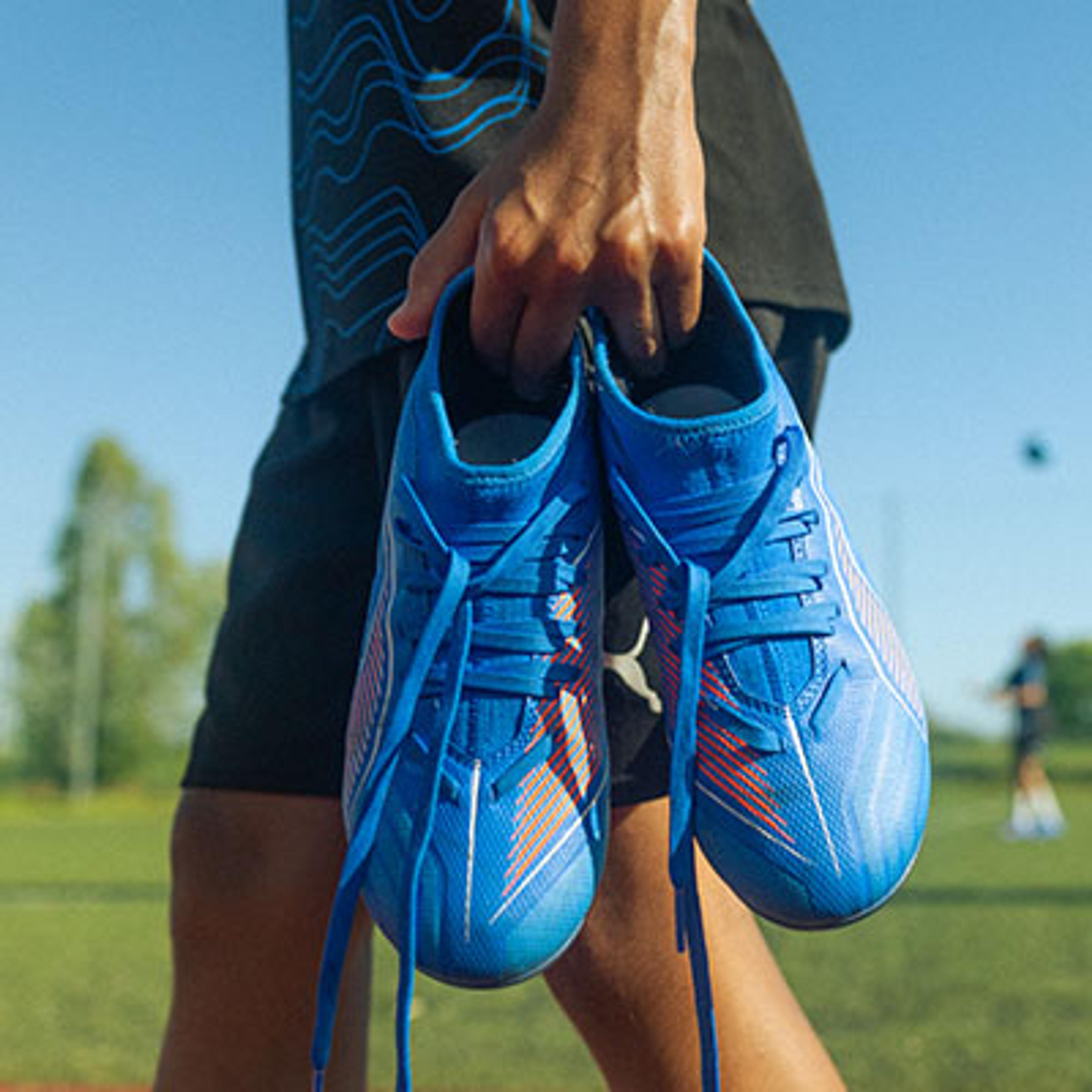 a person is holding a pair of blue soccer cleats in their hands .