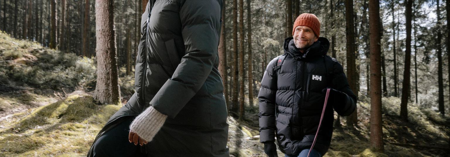 a man and a woman are walking through a forest .