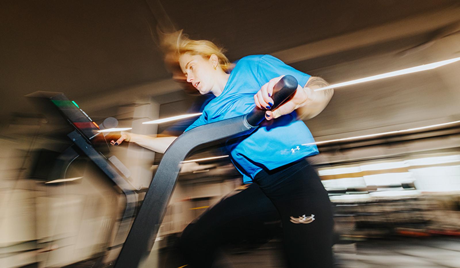 a woman is running on a treadmill in a gym .