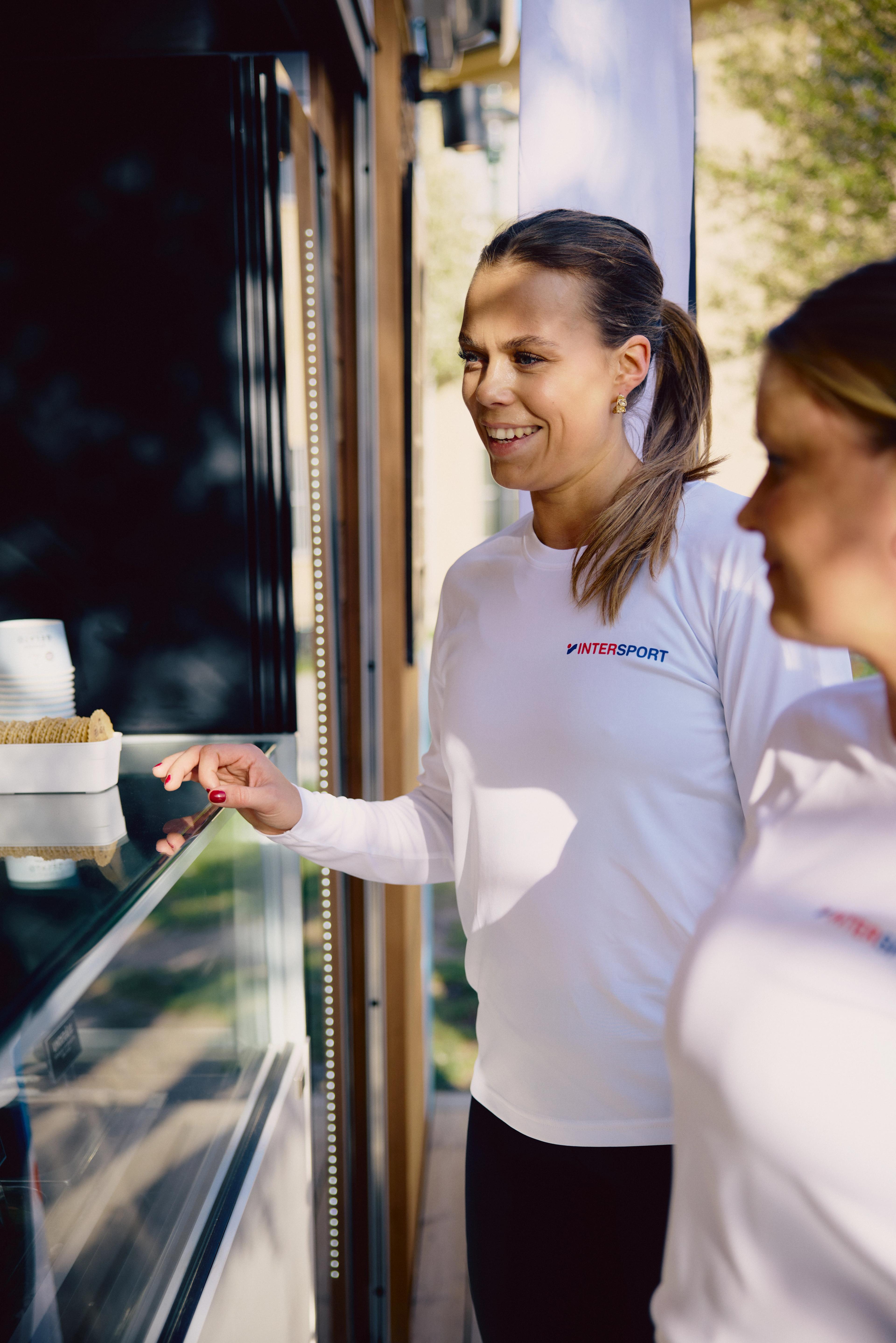 a woman wearing a white shirt with the word intersport on it