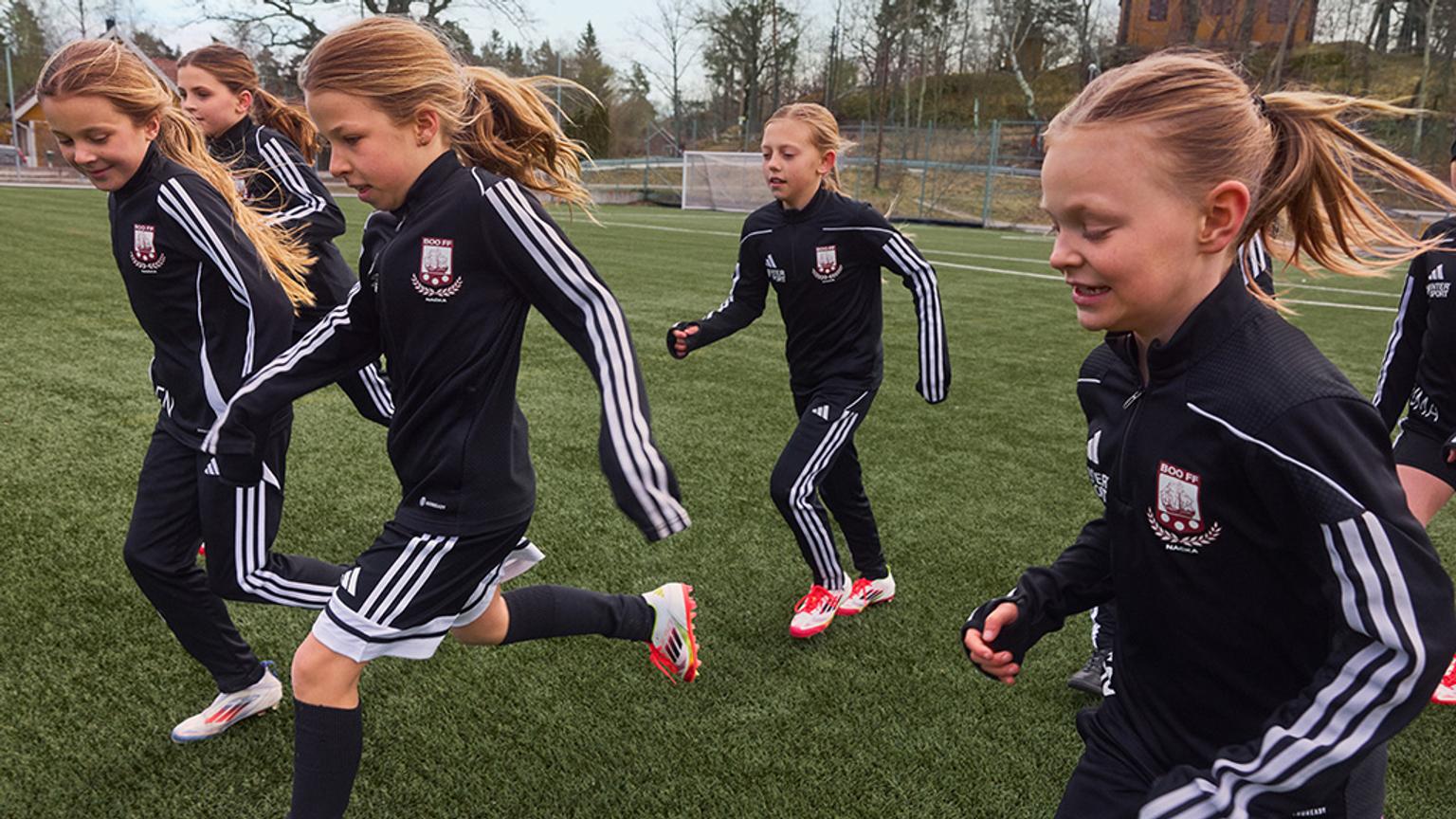 a group of young girls are running on a soccer field .