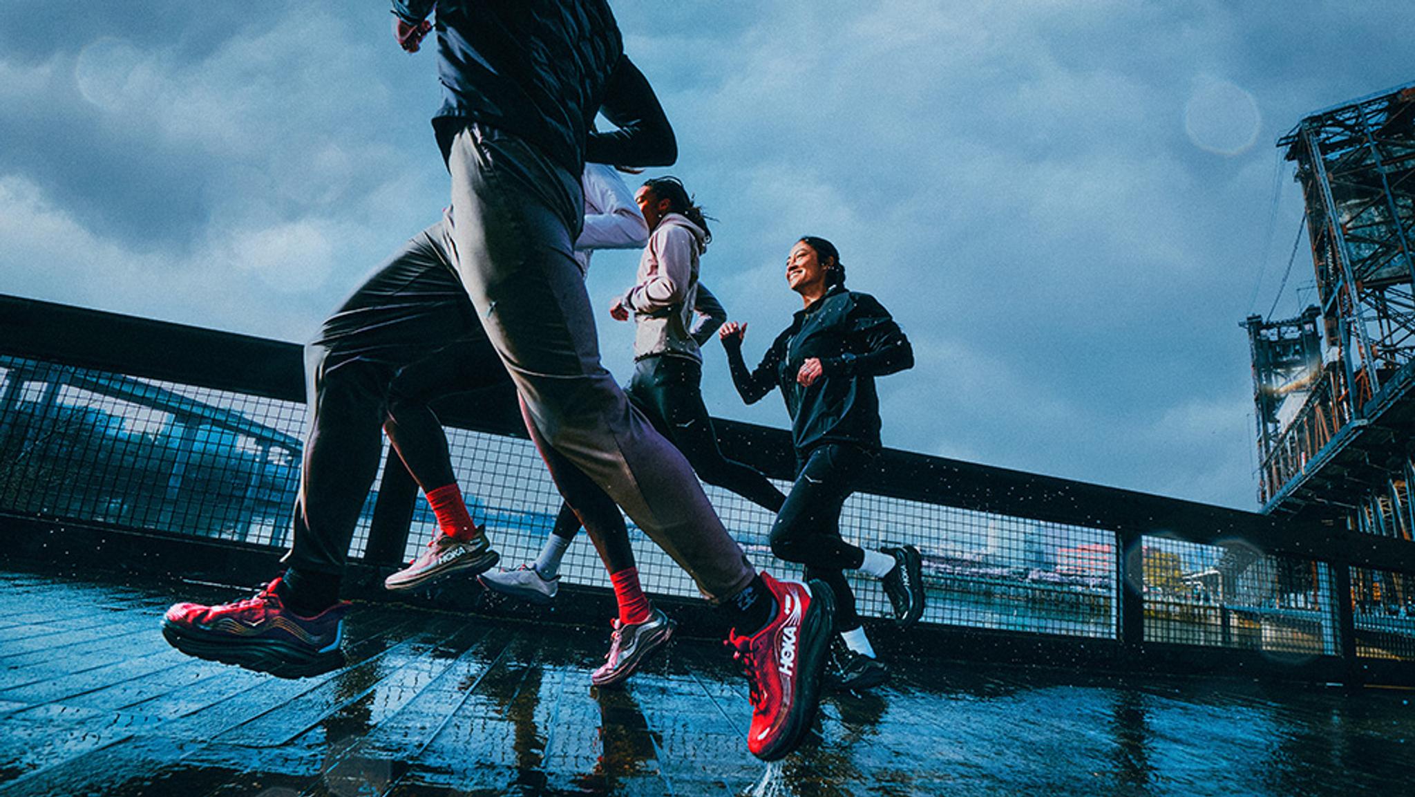 A group of runners on a wet path under a dark, cloudy sky.