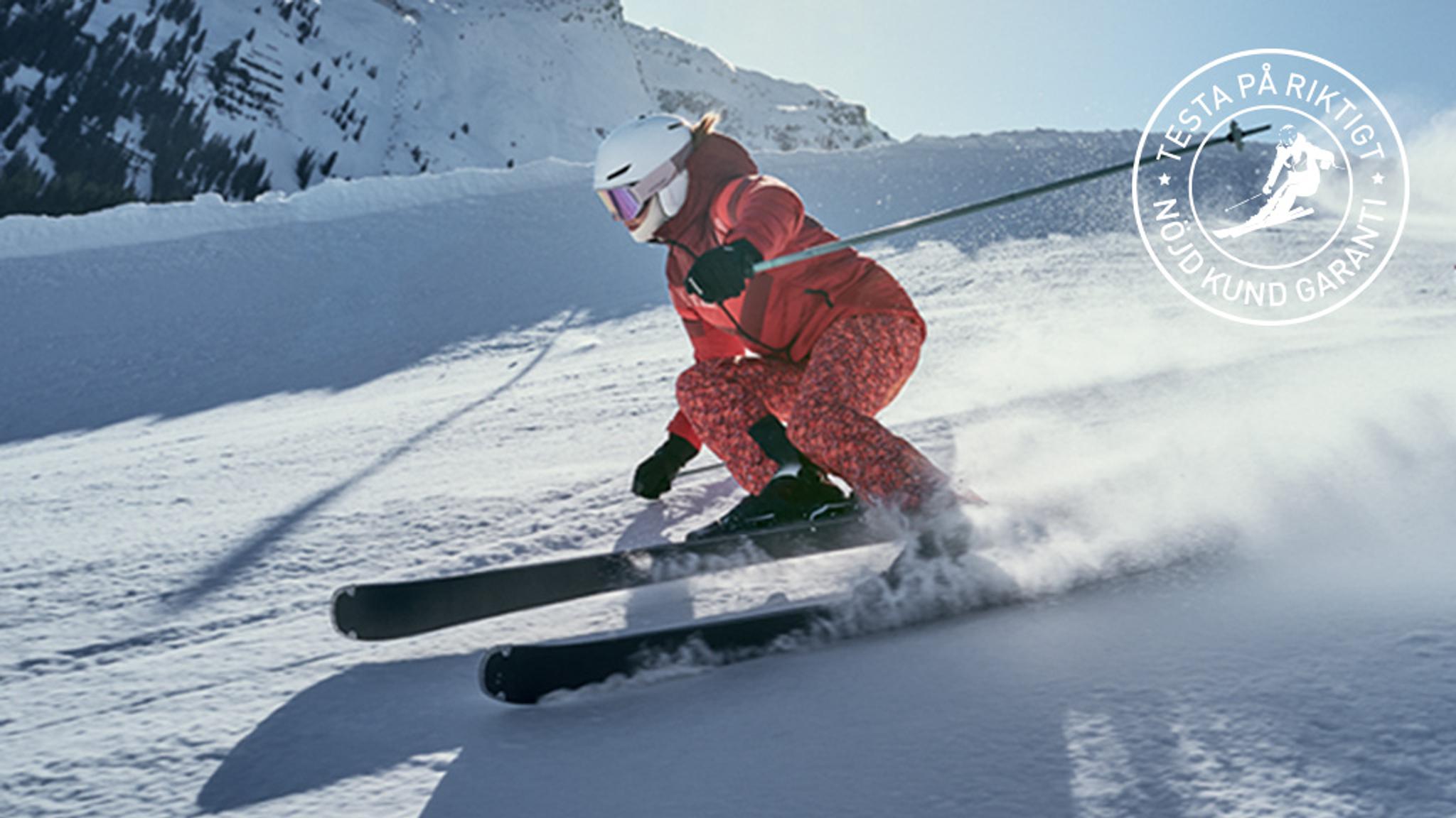 Skier in red outfit carves down a snowy slope, spraying snow, with a 'Test for real, Satisfied customer guarantee' badge.