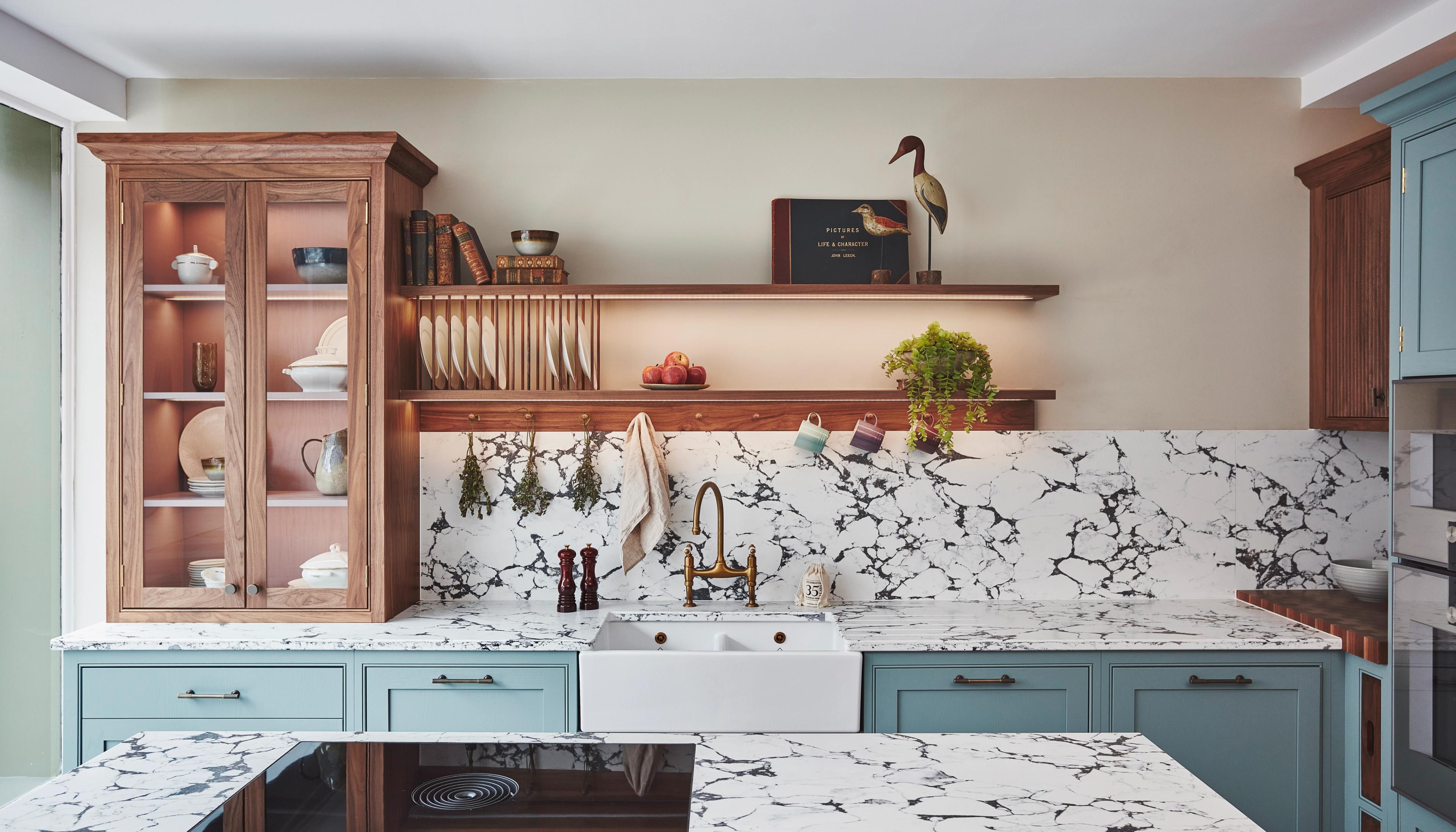 blue kitchen with walnut shelving and counter standing cabinets. Counters are marble