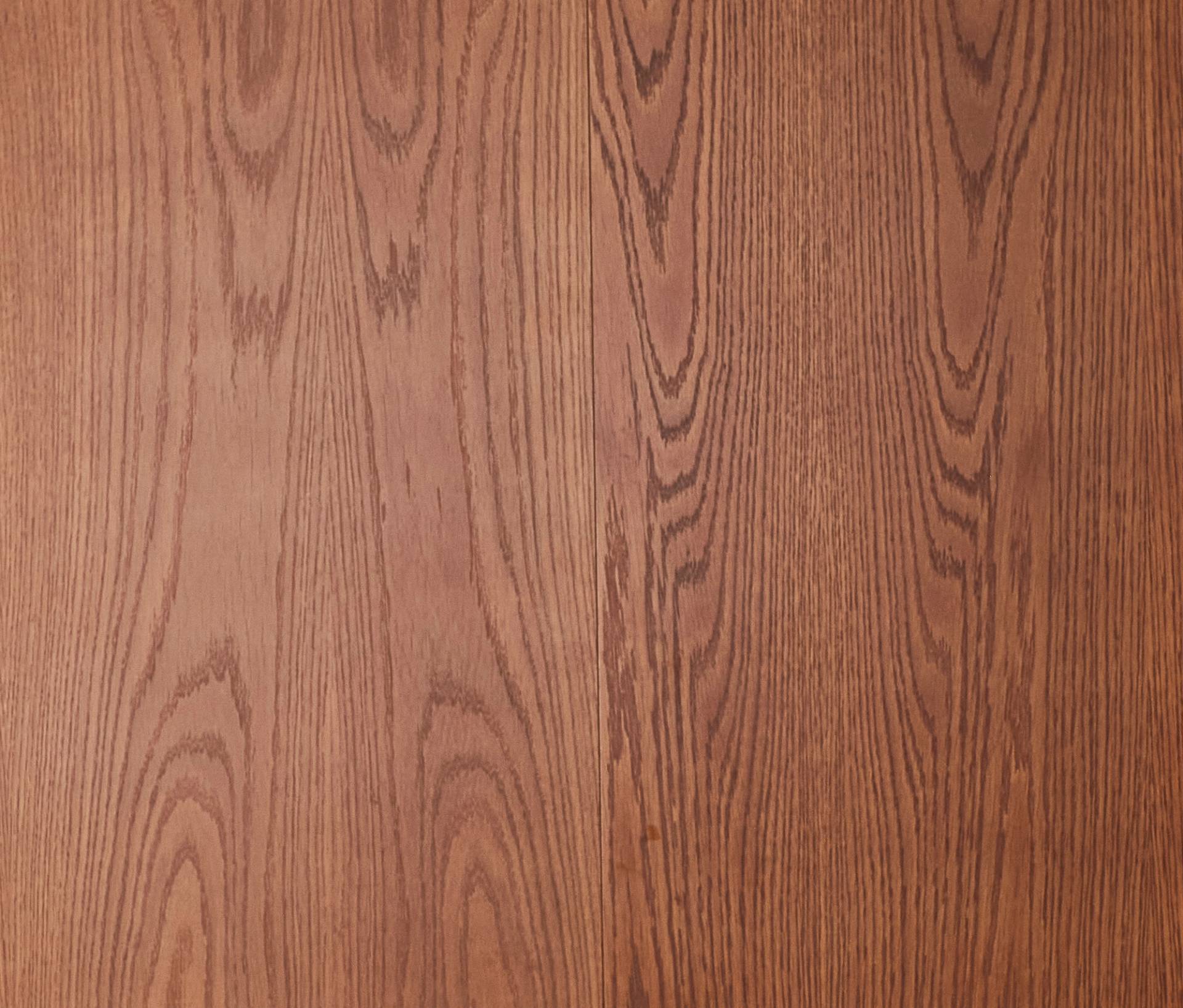 Wooden surface with a natural, light brown finish and visible grain patterns running vertically. The texture and color suggest a polished, traditional wood panel.