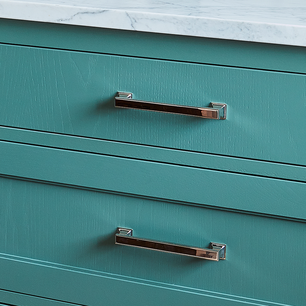 Teal-colored drawers with sleek silver handles and a white marble countertop on top.
