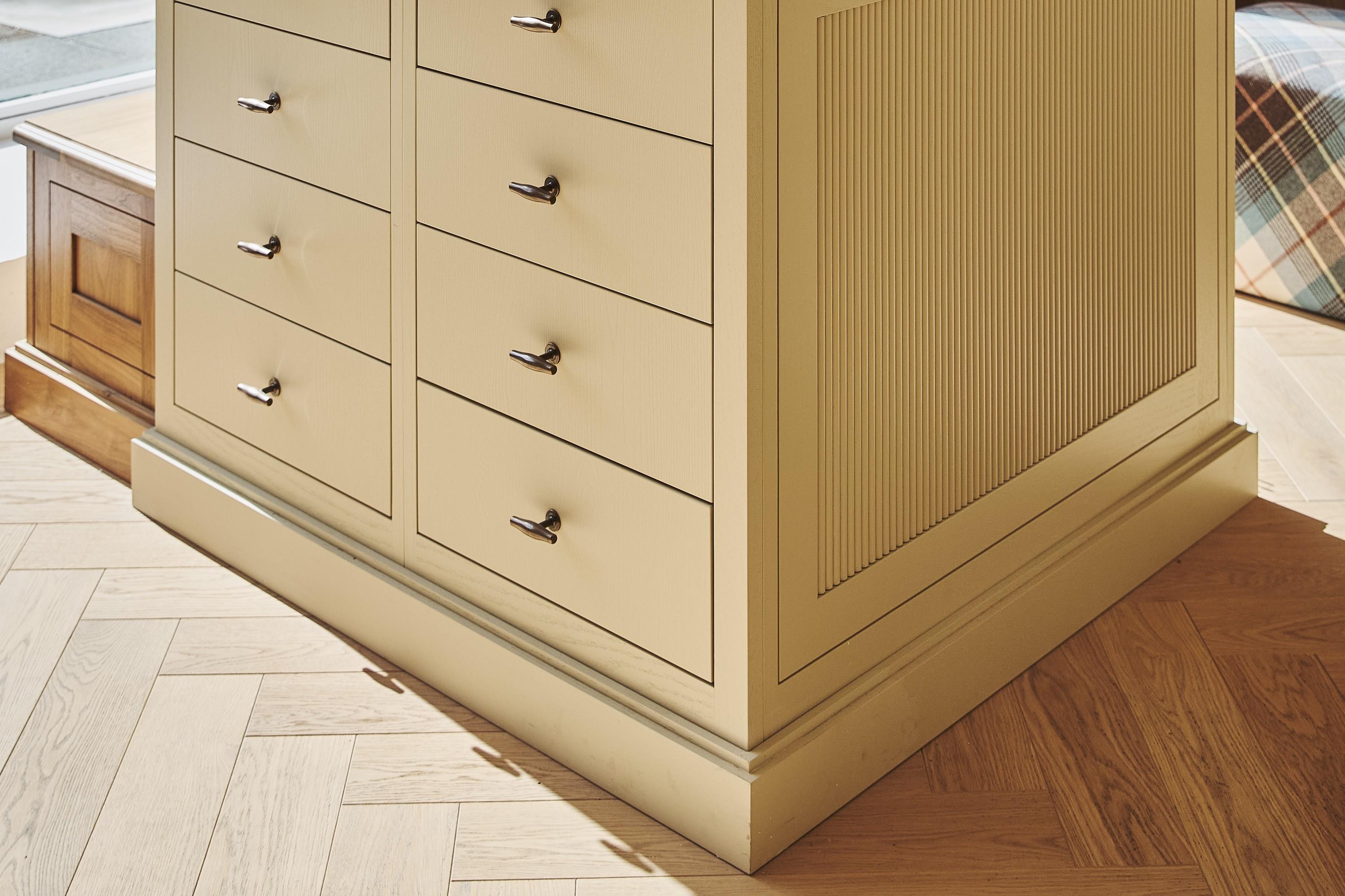 Painted kitchen island with a reeded end panel and timber top in the Naked Kitchens Chelsea showroom, on a herringbone oak floor by Waxed Floors
