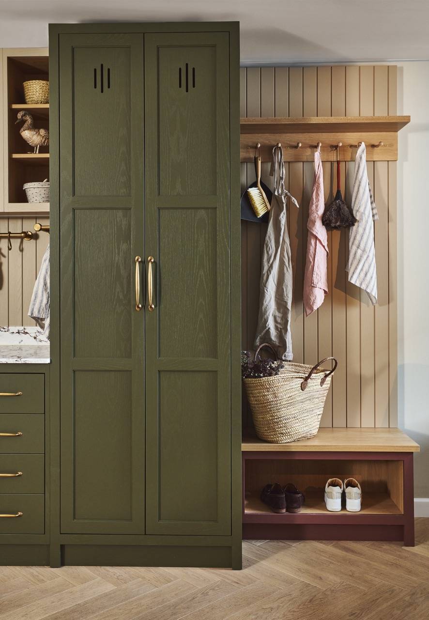 A close-up of a wooden drawer partially open with a leather handle. Inside, there are neatly folded clothes. The drawer is part of a gray dresser with a marble countertop. A green hat is visible on top of the dresser.
