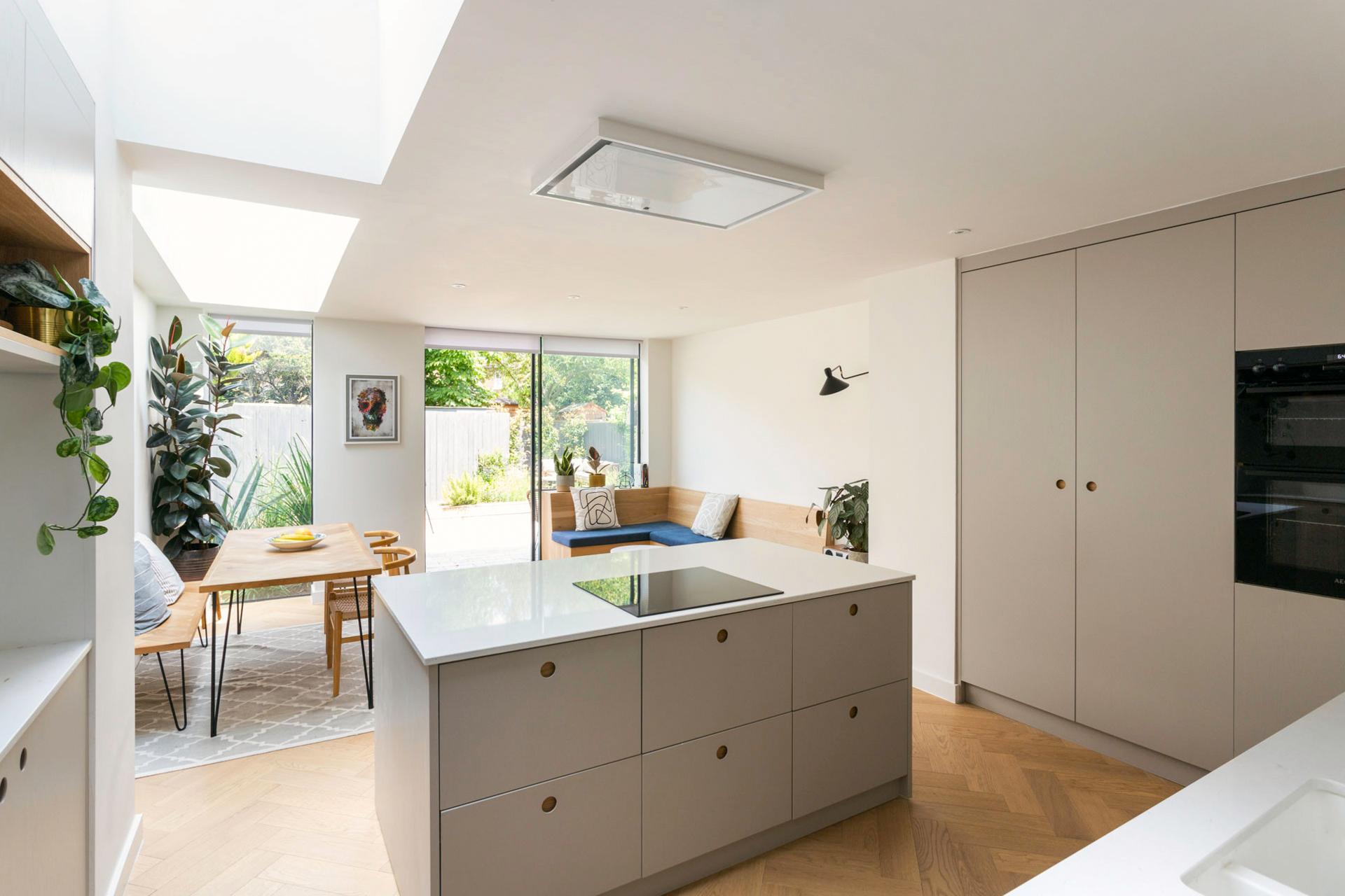 A glimpse into the Camberwell kitchen, showcasing the interplay of dove grey cabinetry, white quartz worktops, and delicate Ladbroke handles, creating a seamless and inviting ambiance.