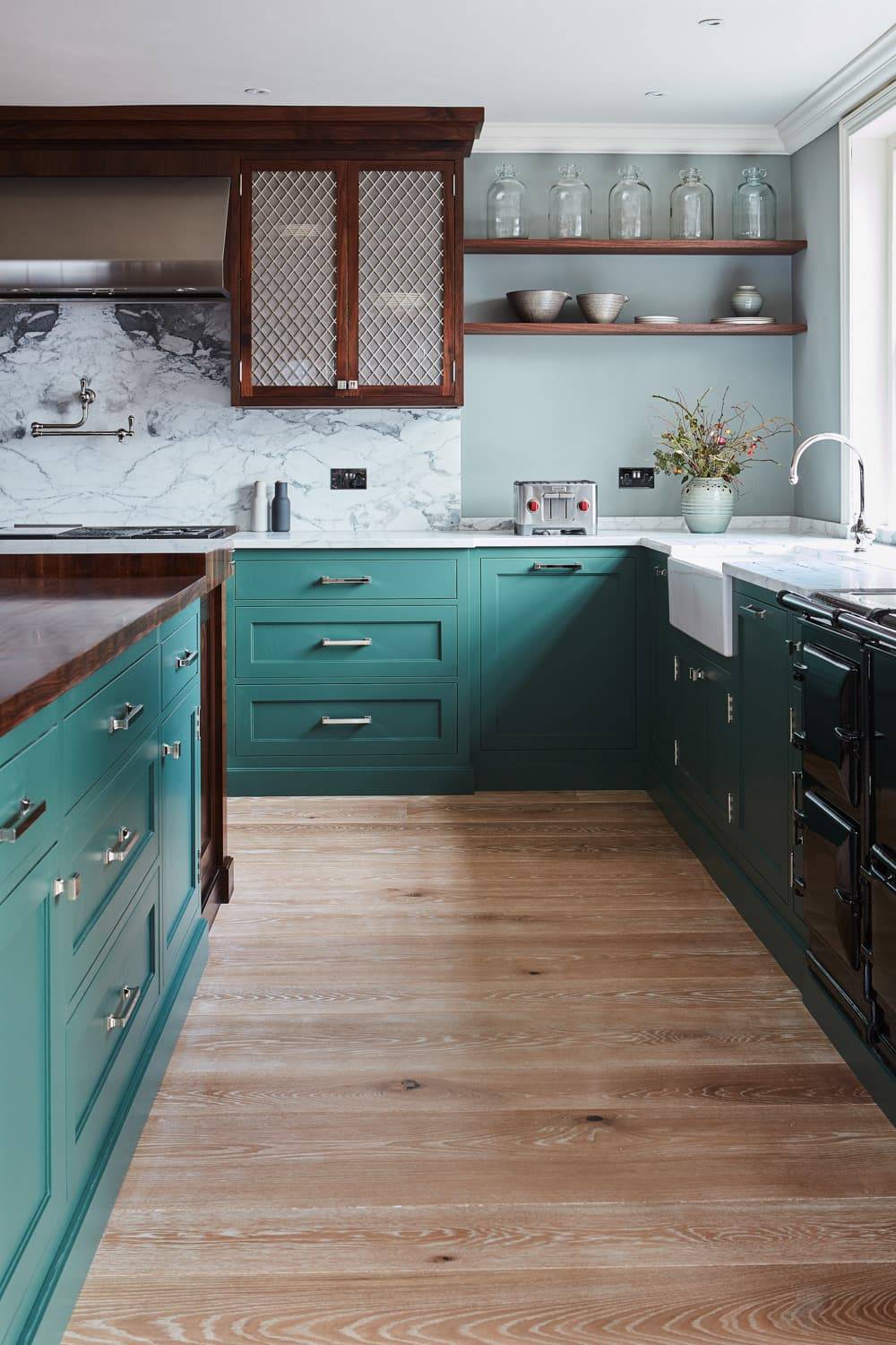 The Georgian Hall kitchen exudes timeless elegance, blending green Shaker cabinetry with white marble countertops, walnut worktops, mesh centrepieces, and a central island. The kitchen's simplicity and functionality make it a perfect centrepiece for any home.