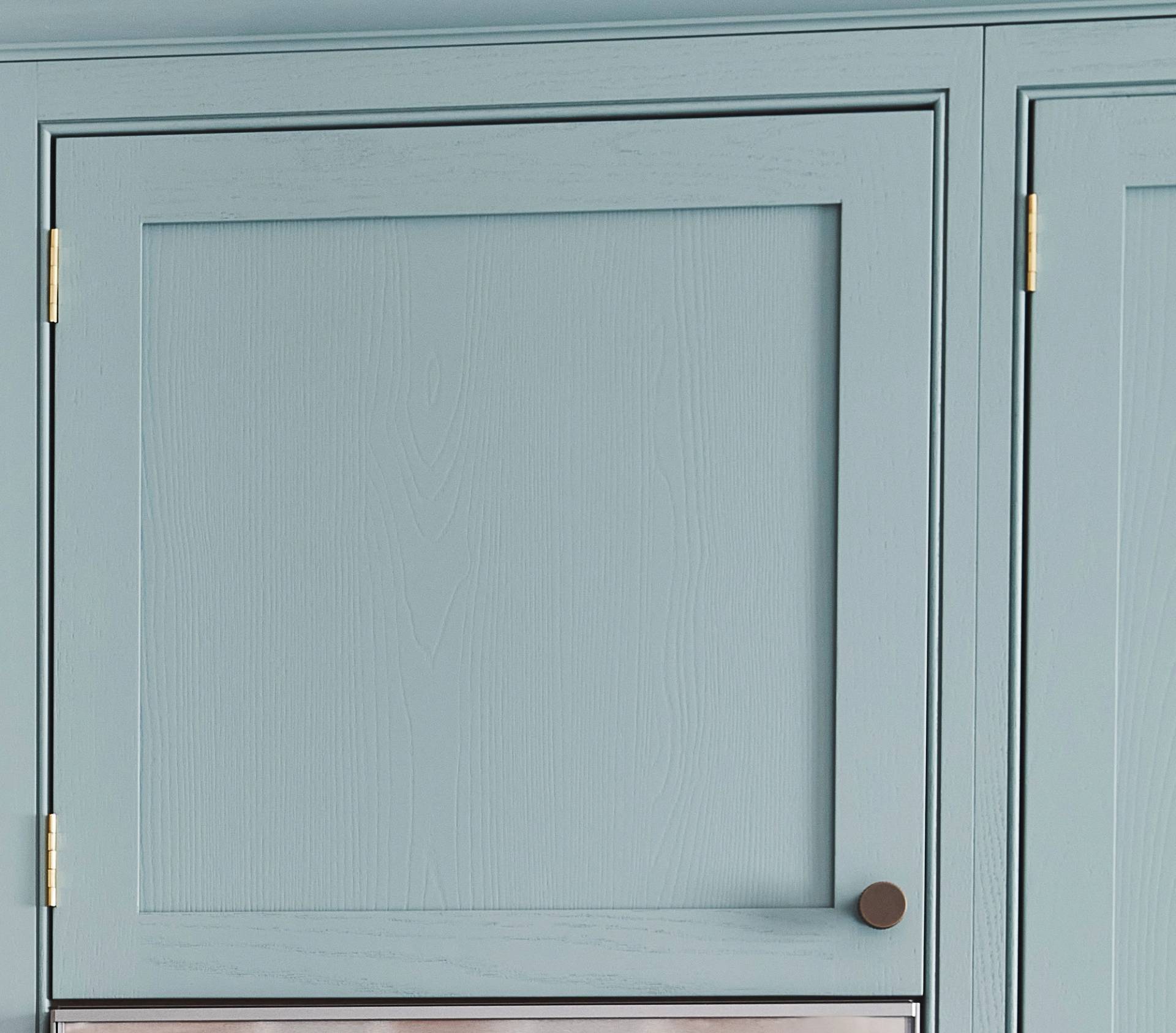 Light blue kitchen cabinet with a wood grain pattern. It has a simple design with a round, dark metal knob. Golden hinges attach the cabinet door to the frame.