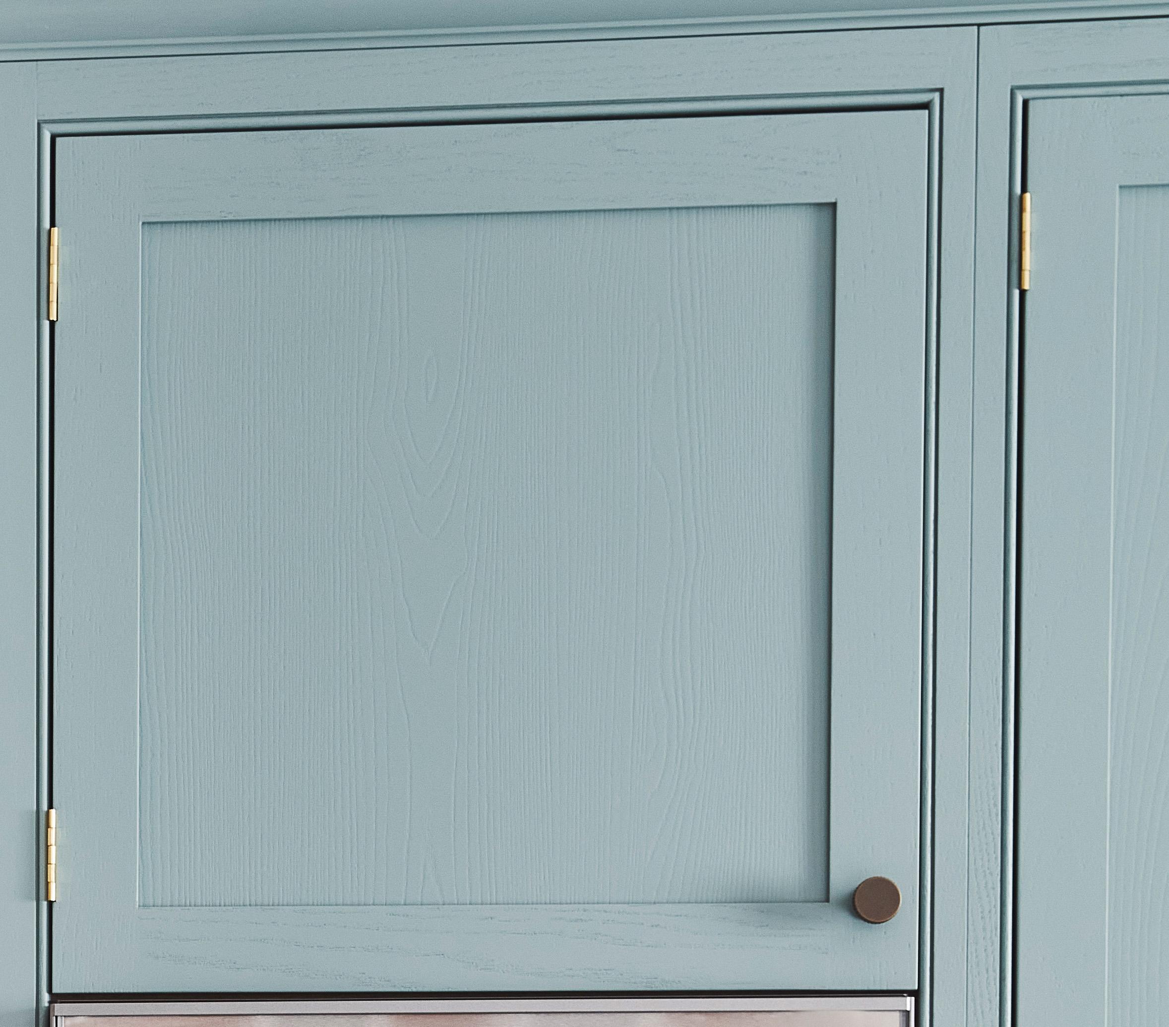 Light blue kitchen cabinet with a wood grain pattern. It has a simple design with a round, dark metal knob. Golden hinges attach the cabinet door to the frame.