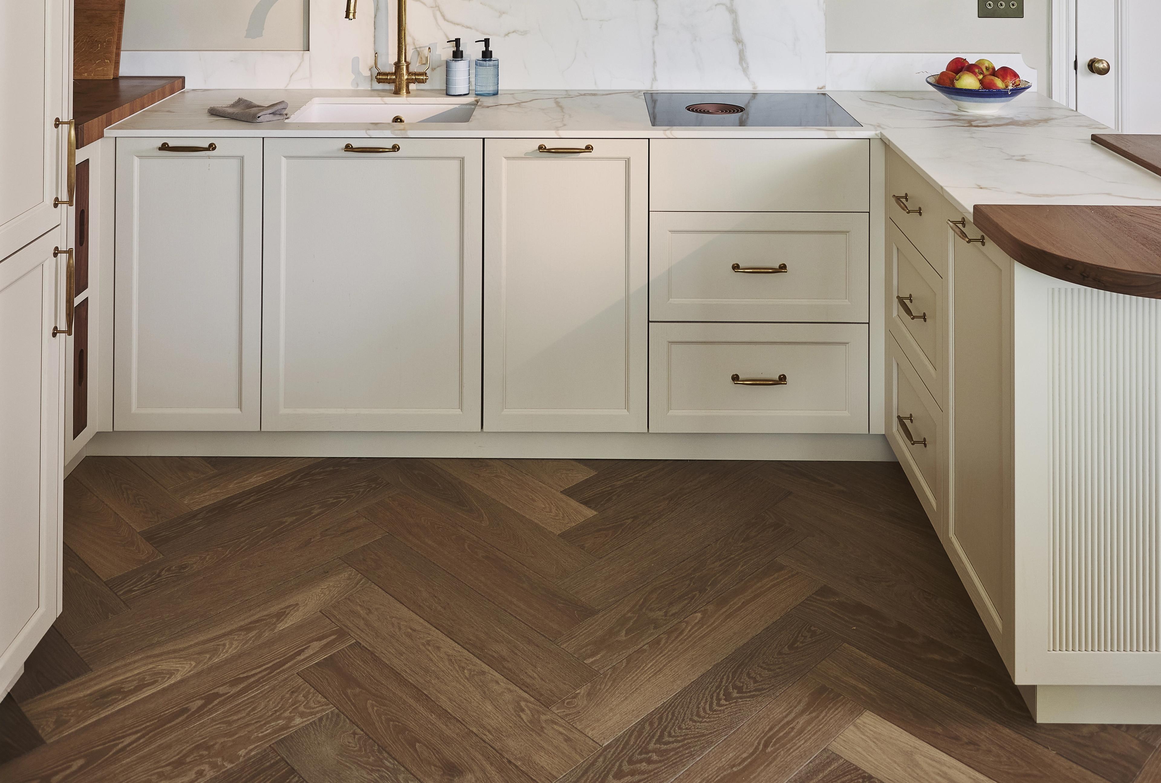 Old Chelsea kitchen by Naked Kitchens with cream painted cabinetry, reeded glass wall cabinets and a herringbone oak floor by Waxed Floors