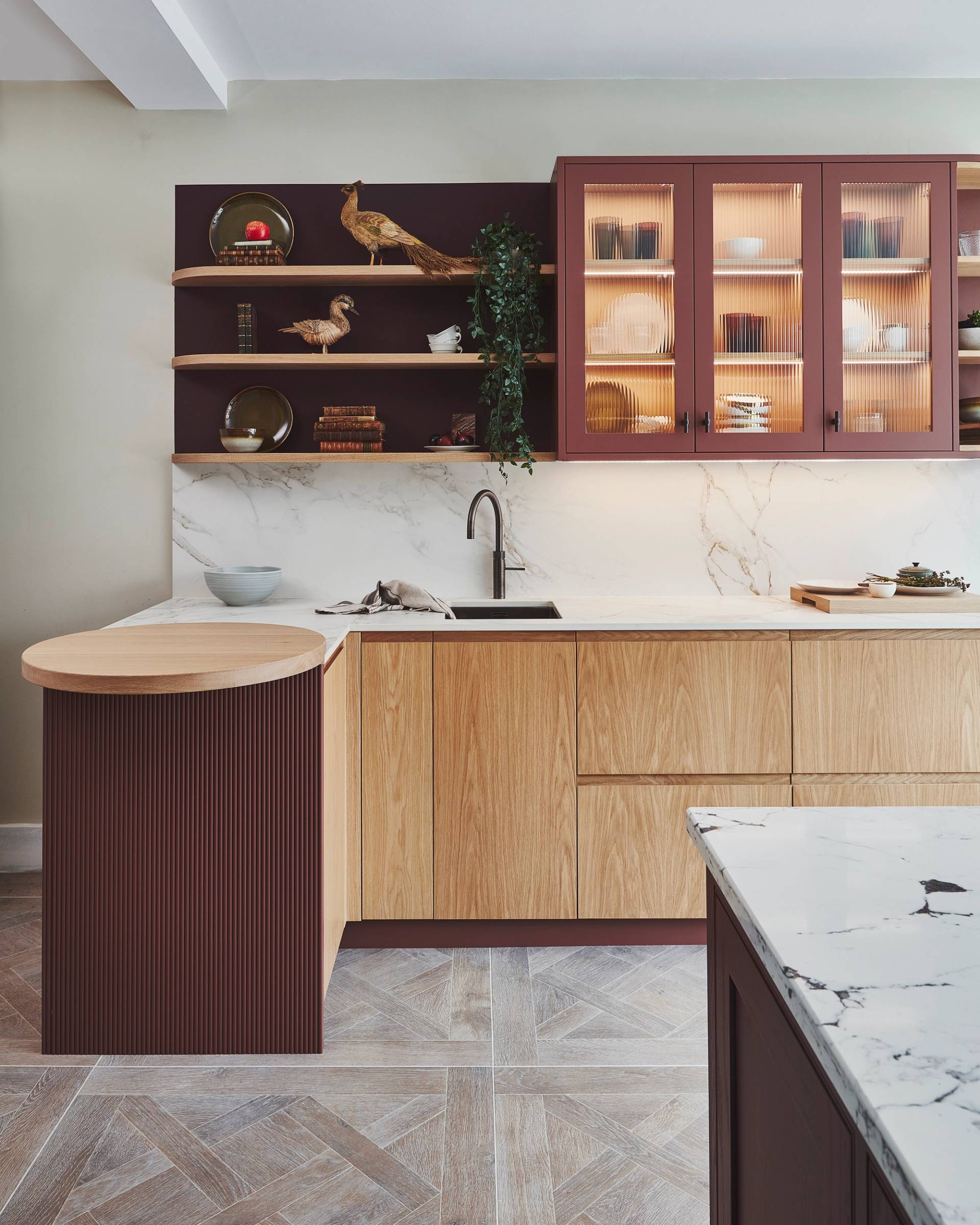 Dark red and oak kitchen, with round wooden counter top on end of run. Curved shelving above.