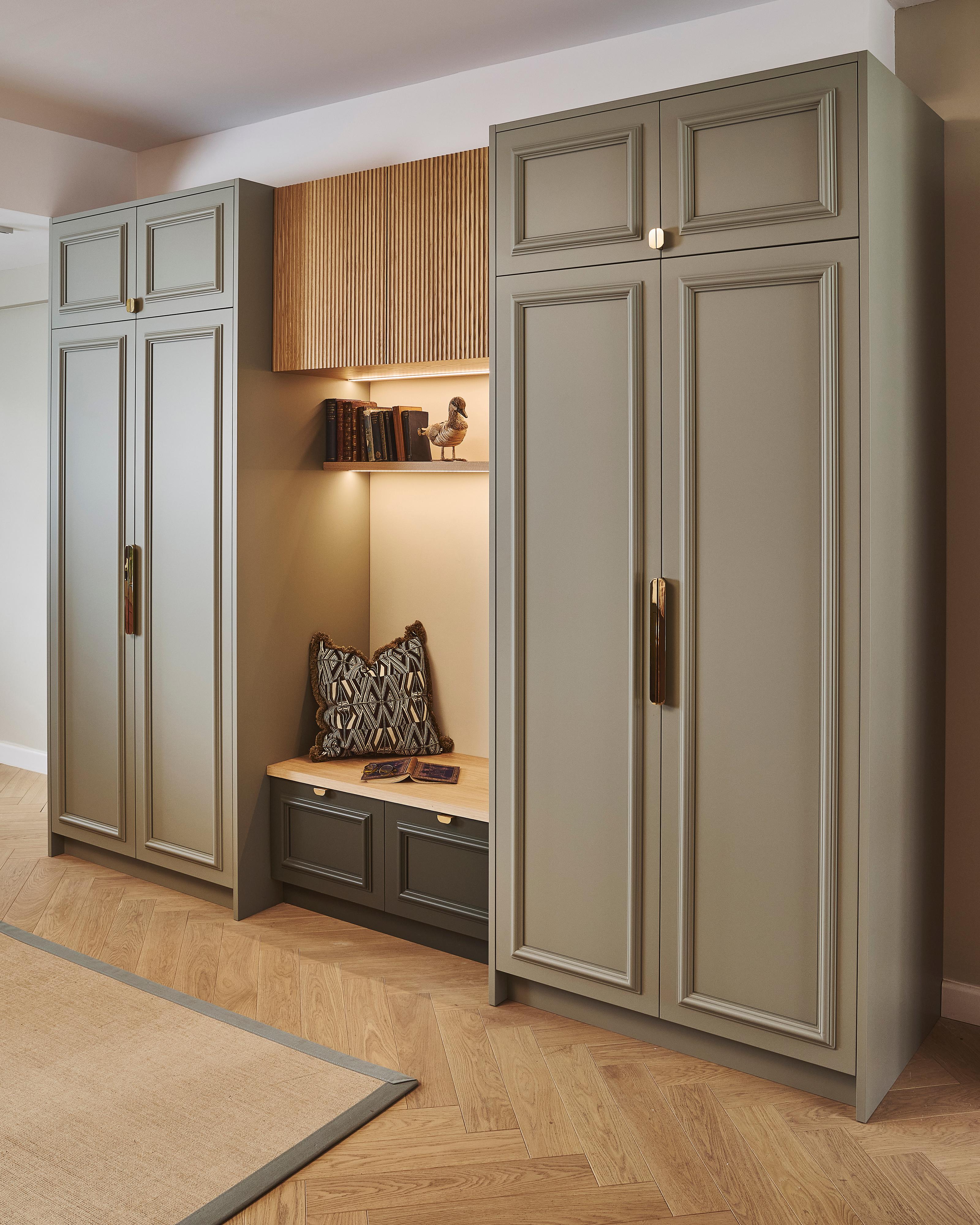 A kitchen with blue cabinets, marble countertops, and a farmhouse sink. Wooden shelves hold dishes, plants, and decorative items. A tall cabinet displays more dishes. A backsplash with a black and white pattern complements the design.