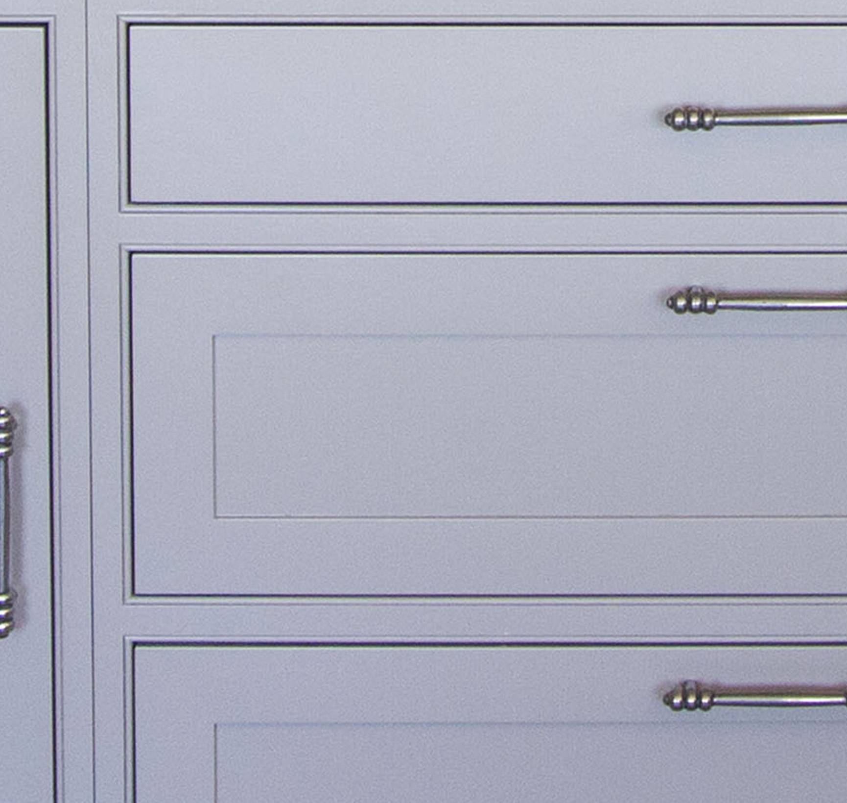 Close-up of light gray cabinet drawers and doors with decorative silver handles and simple panel detailing.