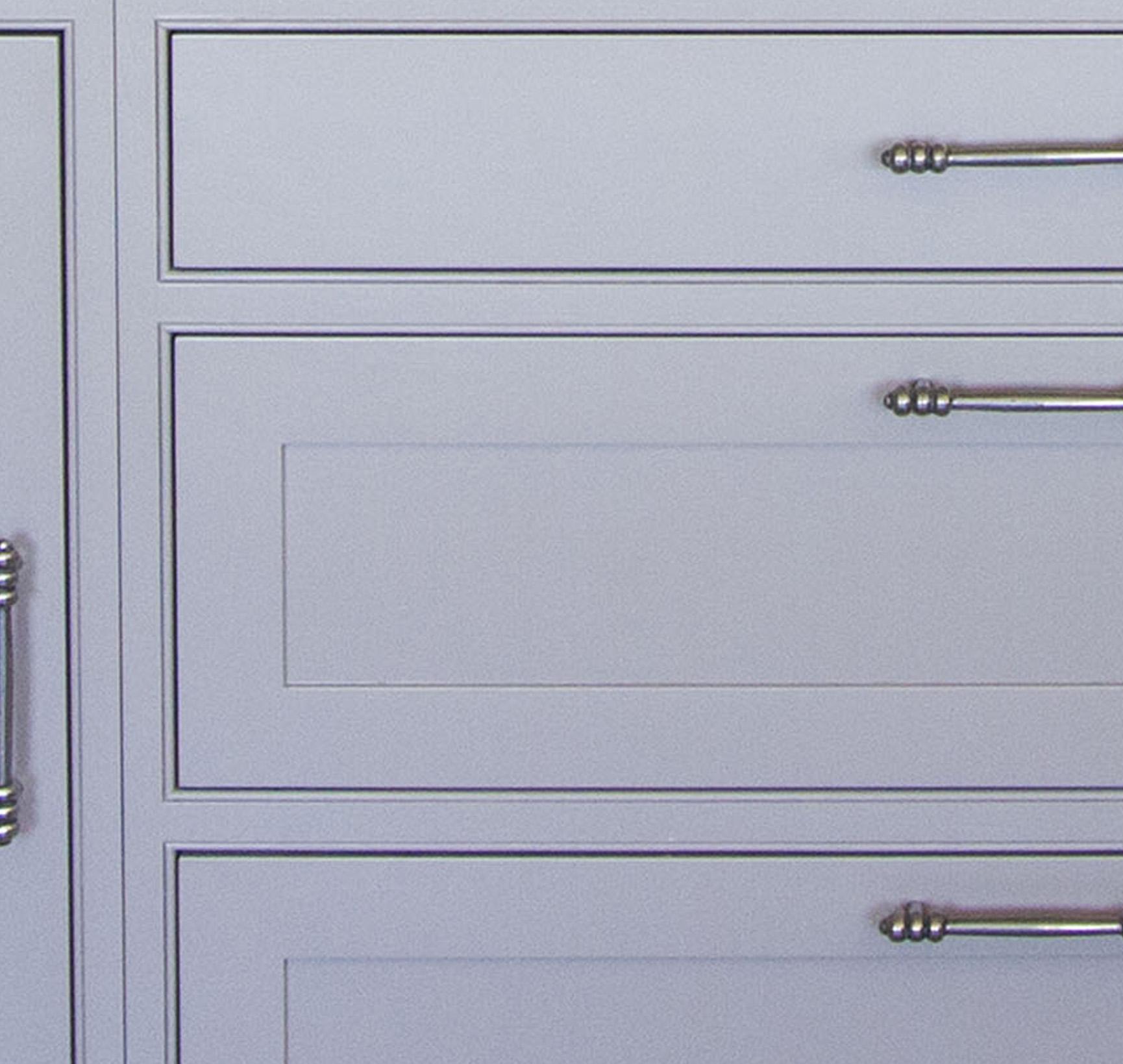 Close-up of light gray cabinet drawers and doors with decorative silver handles and simple panel detailing.