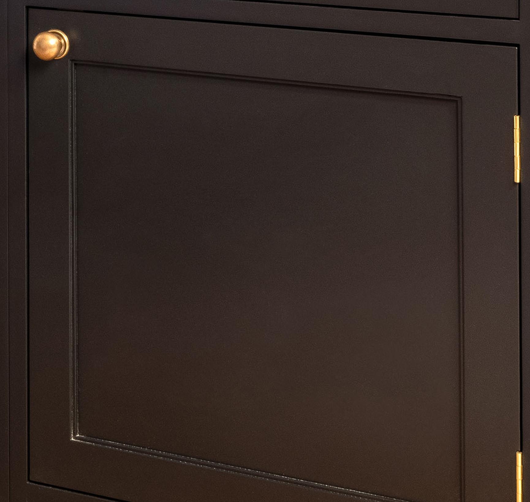 A close-up of a dark brown cabinet door with a gold knob on the upper left corner and a gold hinge on the right edge. The door has a simple, recessed panel design.