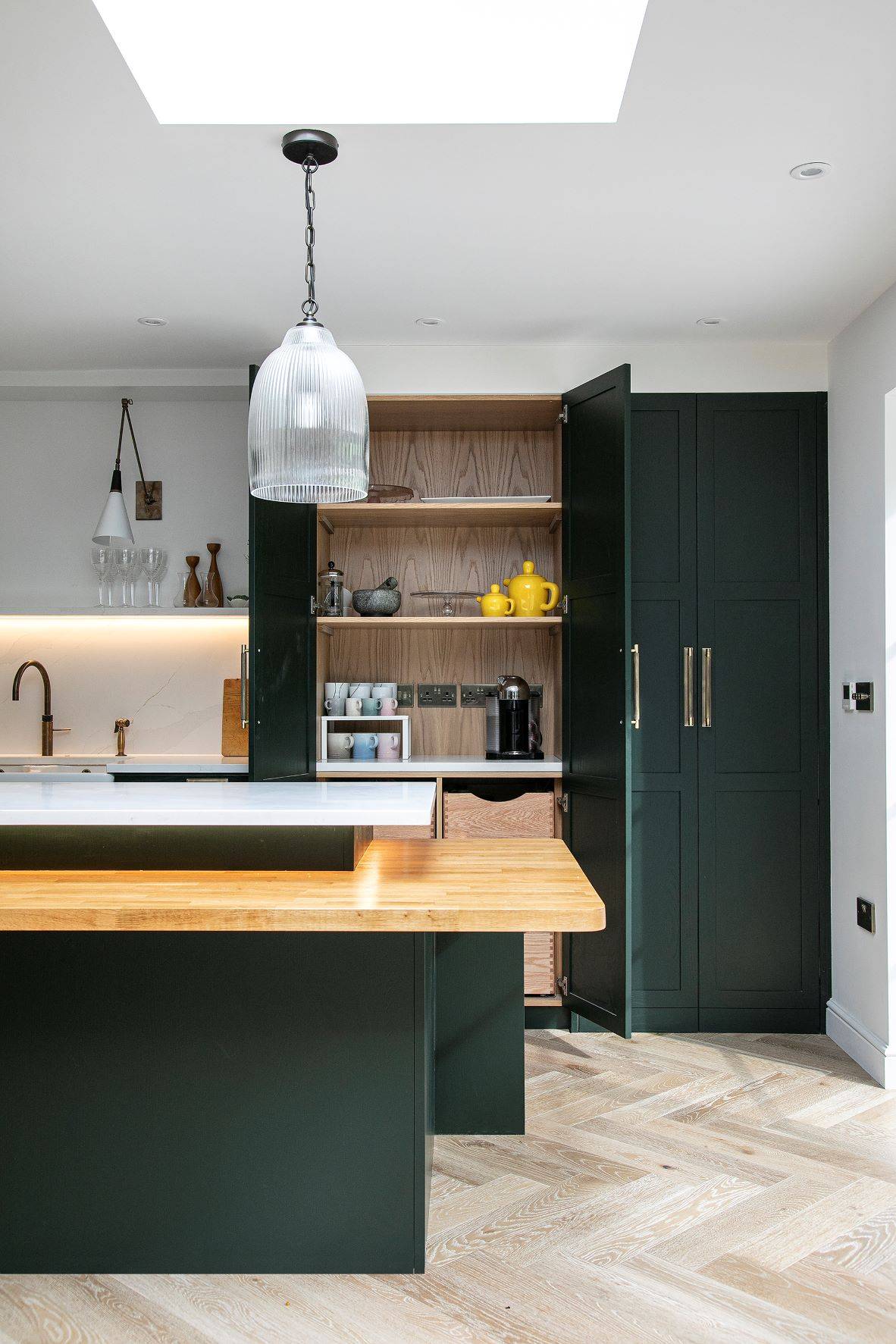 A harmonious blend of Sandringham Pine cabinetry, a modern white backdrop, and a touch of walnut, creating a captivating and luxurious atmosphere in the Westward Ho kitchen.