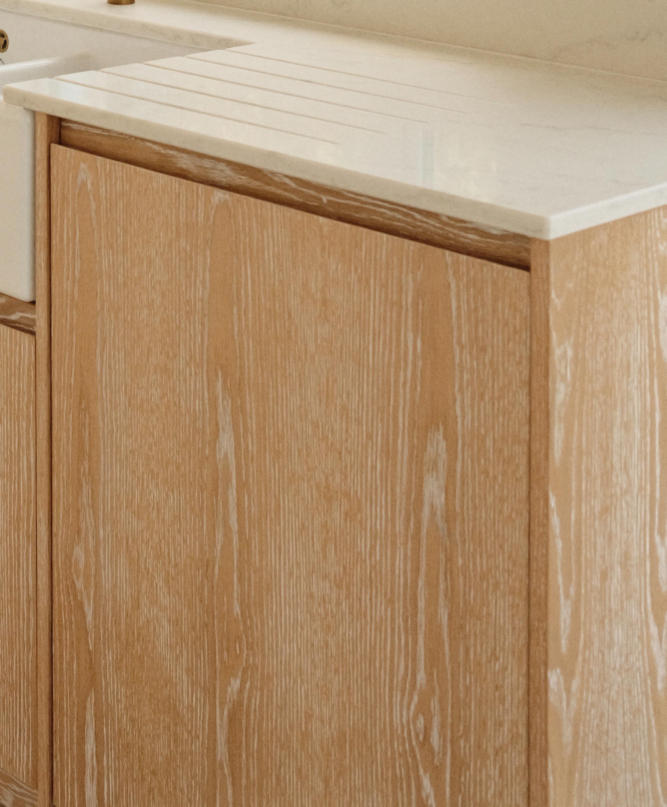 Light wood kitchen cabinet with a white stone countertop and an integrated sink, featuring a minimalist and clean design.