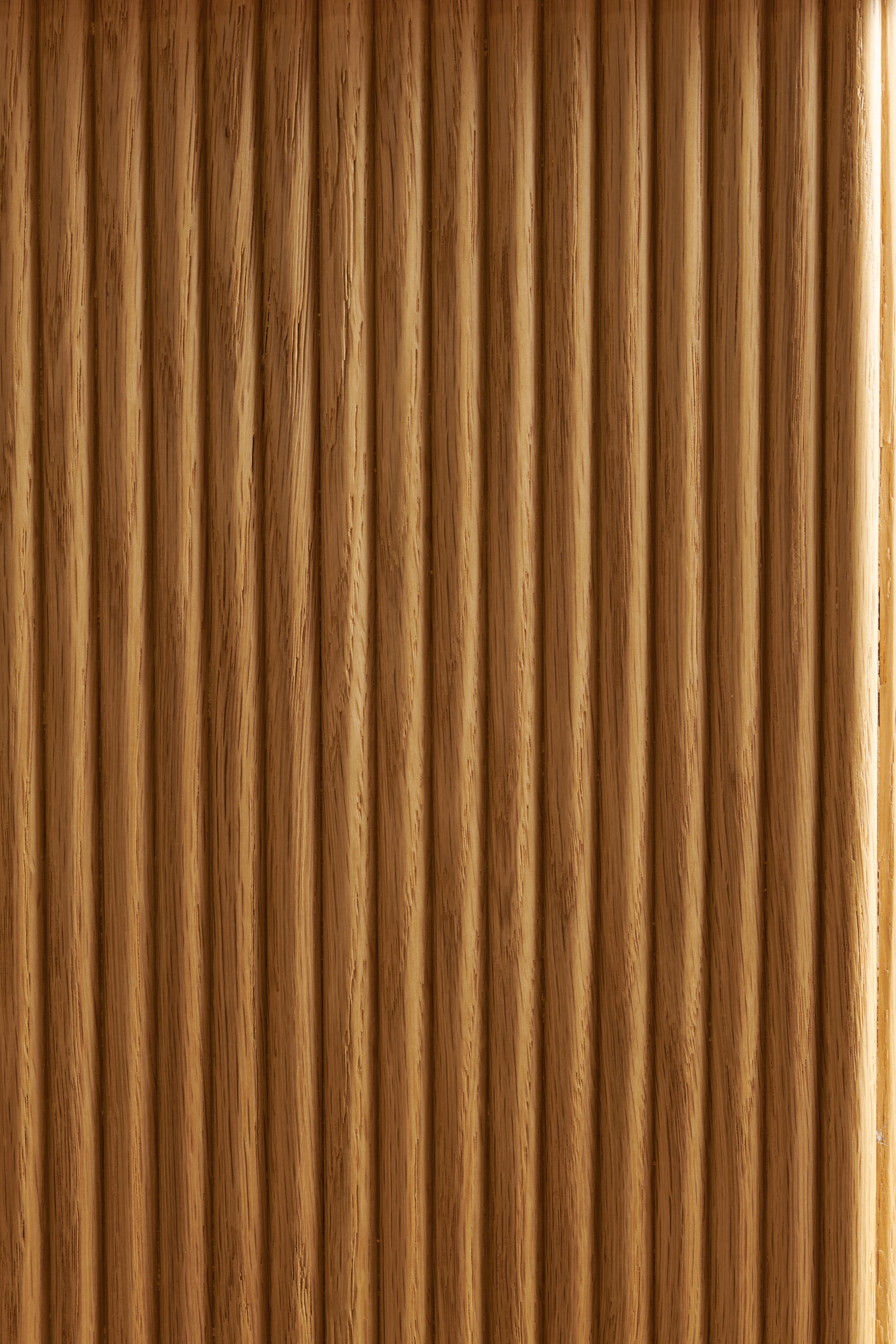 A close-up of a wooden surface with a rich, dark brown color. The texture displays a natural grain pattern with subtle variations in shade, giving it a warm and polished appearance. The surface is smooth and has a glossy finish.