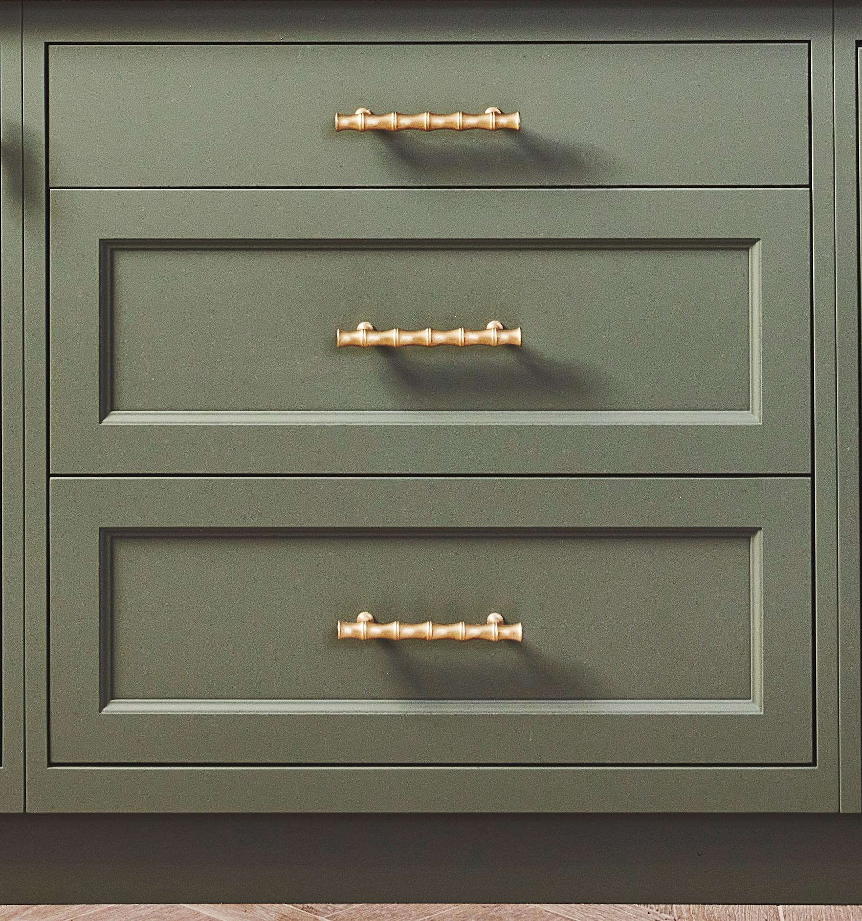 Three olive green cabinet drawers with gold handles, featuring a modern and clean design. The drawers have recessed panel fronts, and the gold handles are horizontally centered on each drawer.