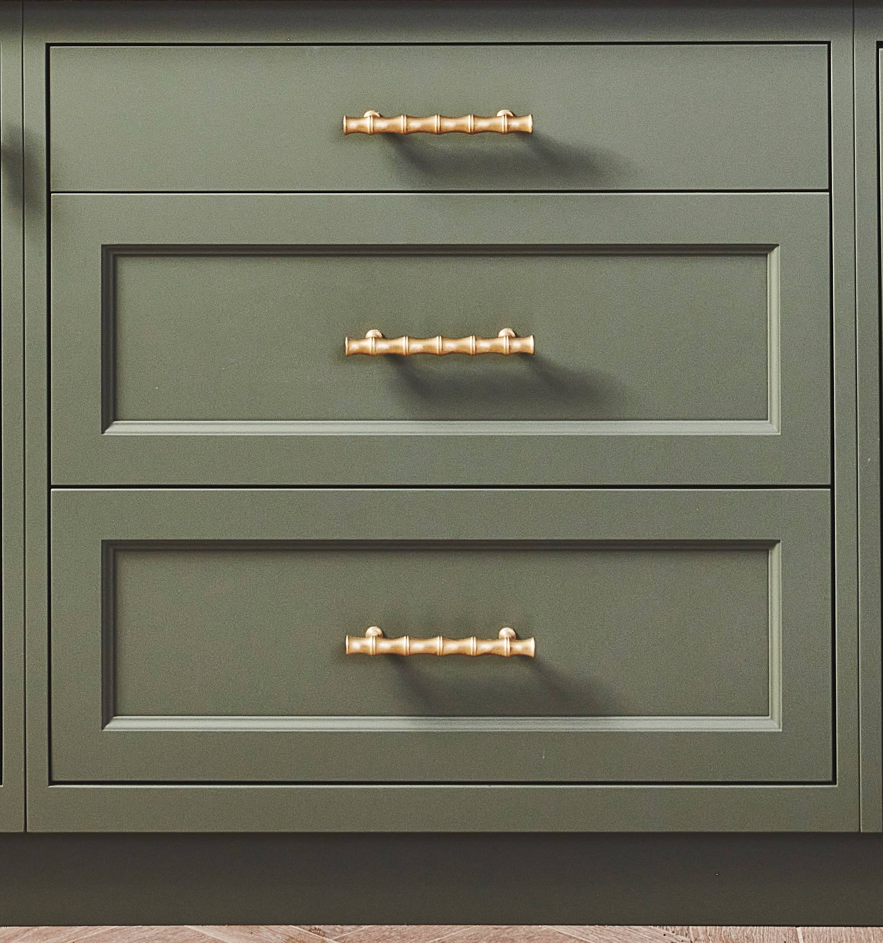 Three olive green cabinet drawers with gold handles, featuring a modern and clean design. The drawers have recessed panel fronts, and the gold handles are horizontally centered on each drawer.