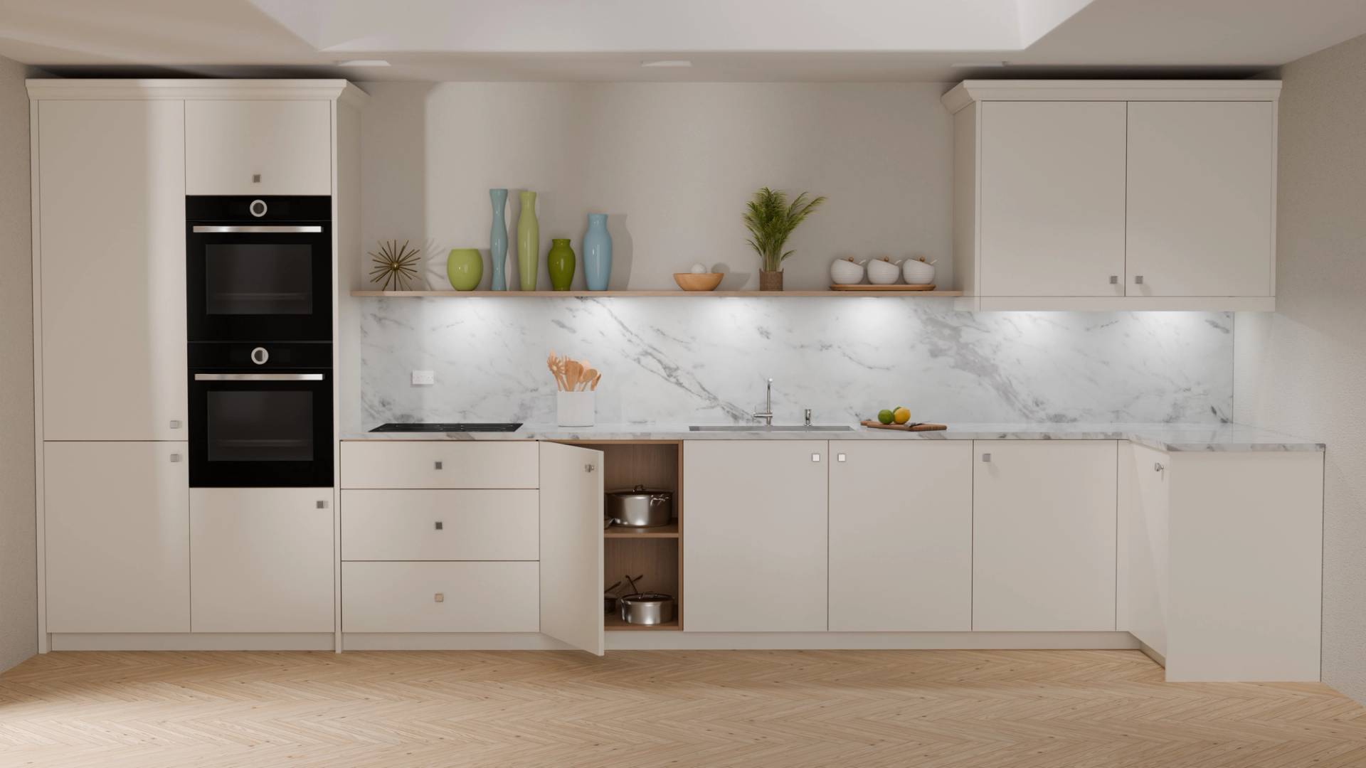 A modern kitchen with white cabinets and a marble backsplash. It features a built-in double oven, light wood flooring, and various decorative items like vases, a plant, fruit, and stacked bowls on the counters. Some cabinet doors are open.